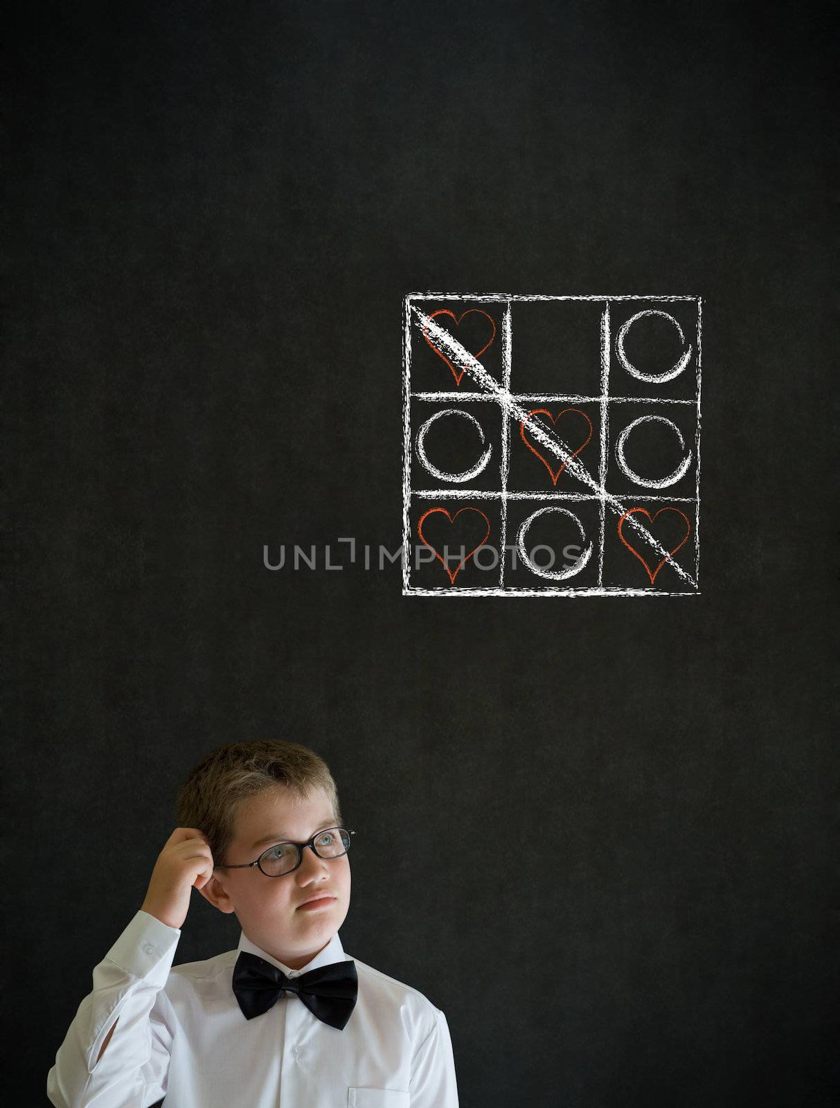 Thinking boy dressed up as business man with chalk tic tac toe love valentine concept on blackboard background