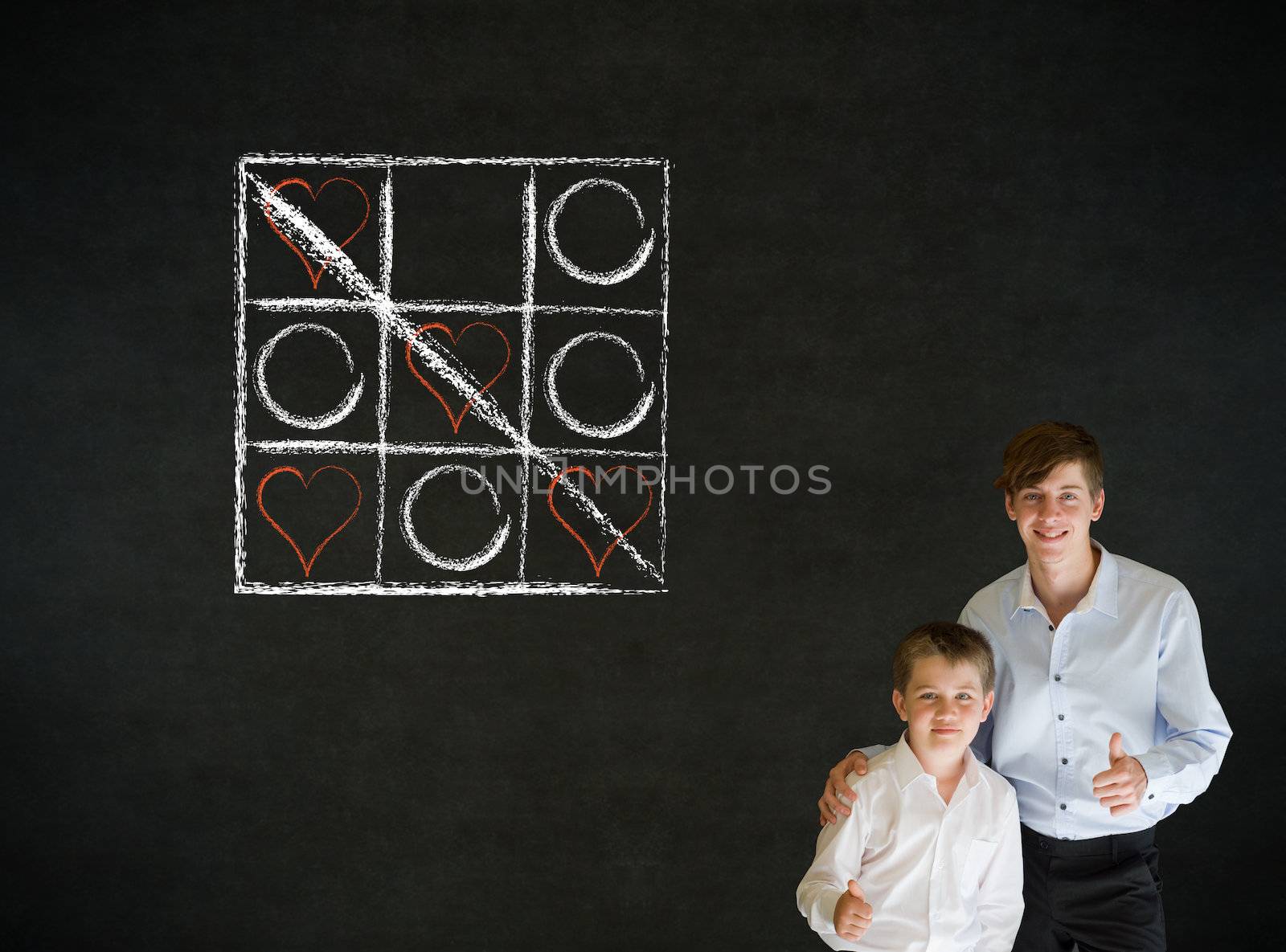 Thumbs up boy dressed up as business man with teacher man and chalk tic tac toe love valentine concept on blackboard background