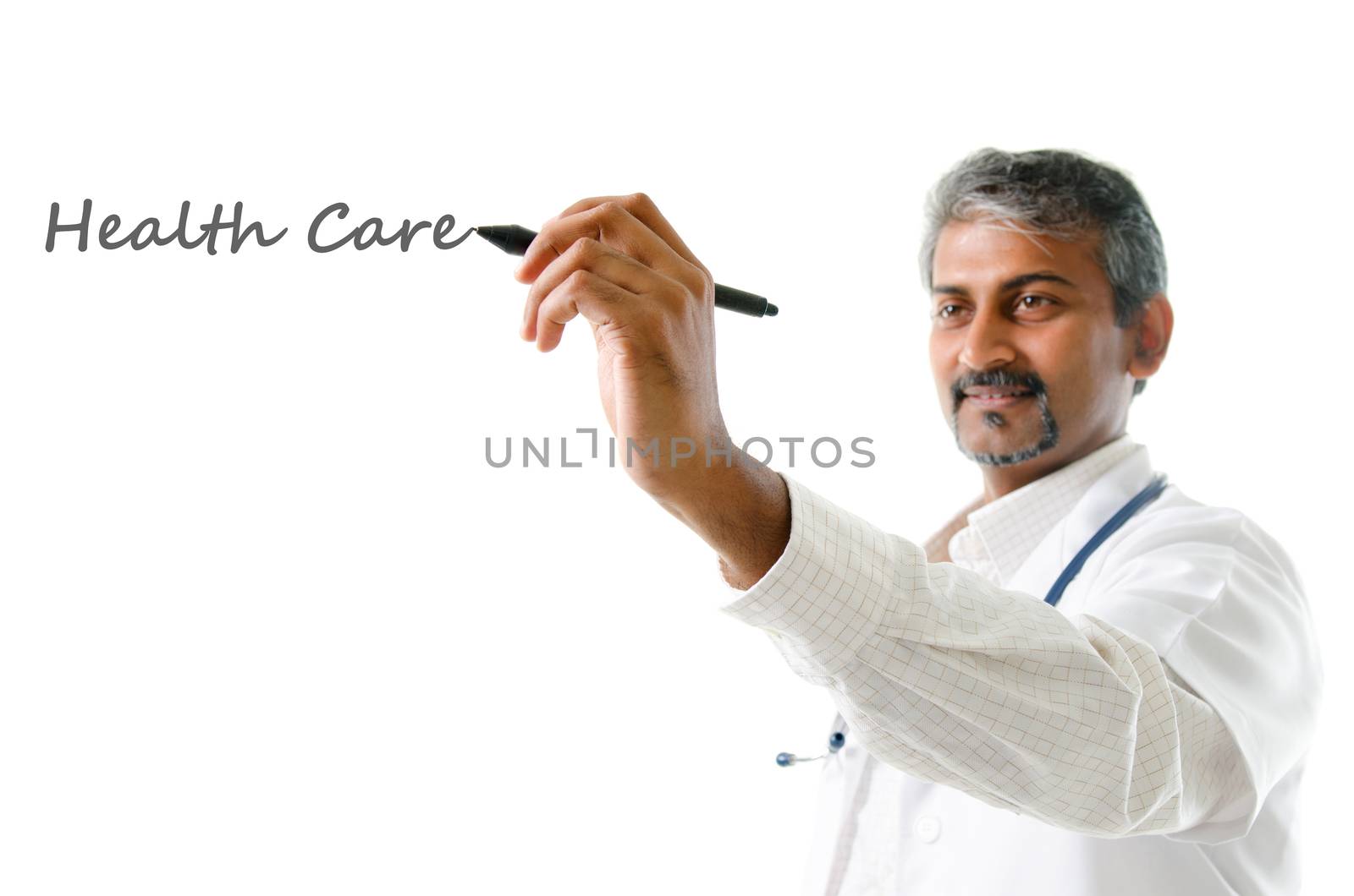 Health care concept. Mature Indian male medical doctor writing on blank space, standing isolated on white background. Handsome Indian model portrait.