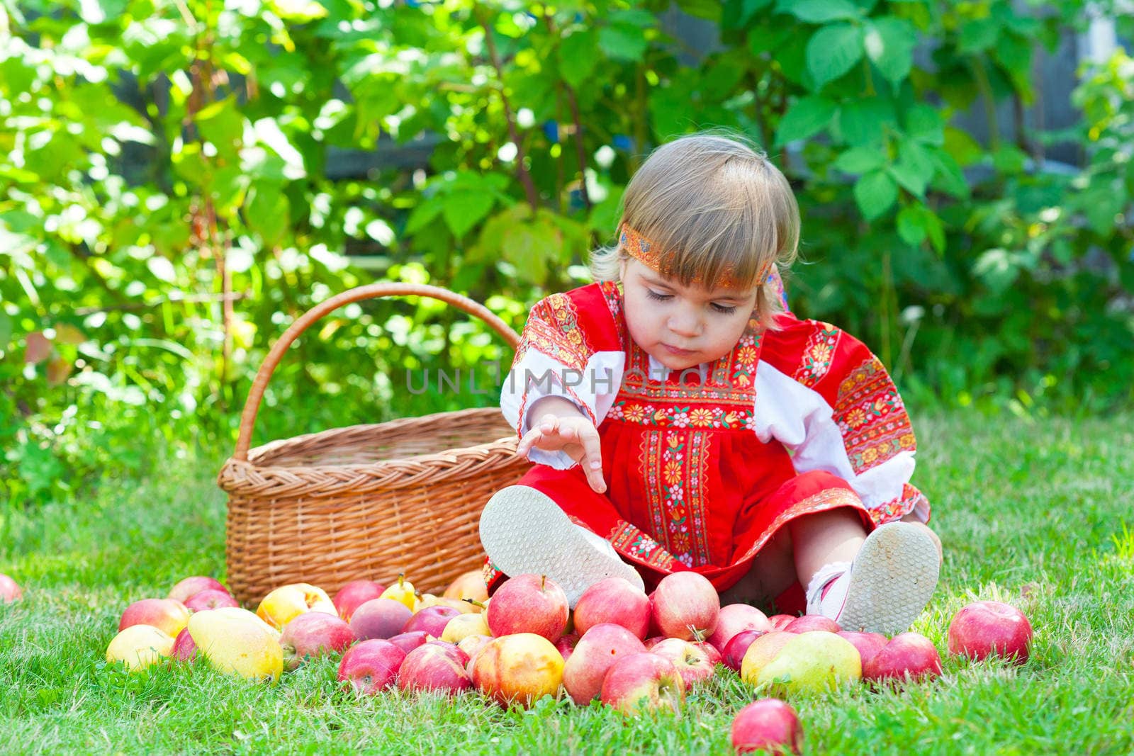 little girl in the Russian national dress with a basket of apples