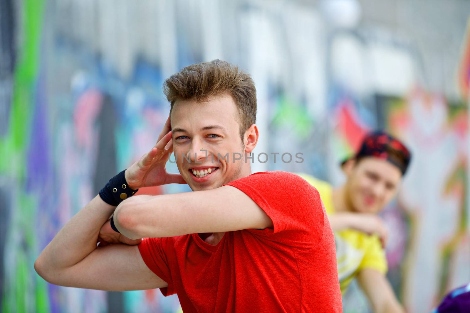 Portrait of happy teens boy with his friend by painted wall looking at camera. Vertical view
