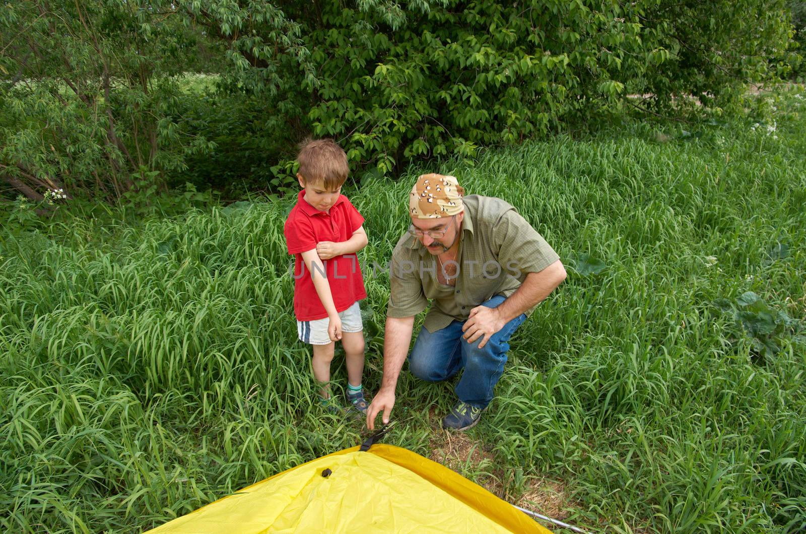 happy Father with children installing their tent on camping site. 