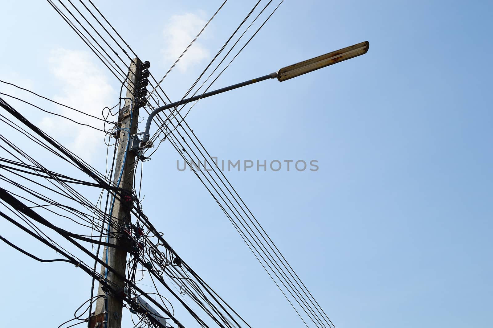 photo of an electric pole with a many cables by Lekchangply