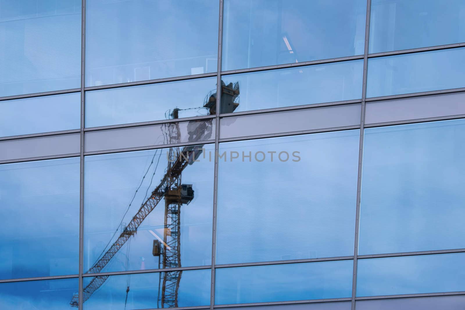 A crane is reflected in a skryscraper glass facade