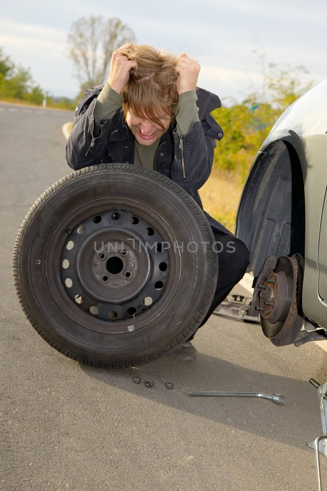 Frustrated man changing wheel on a car