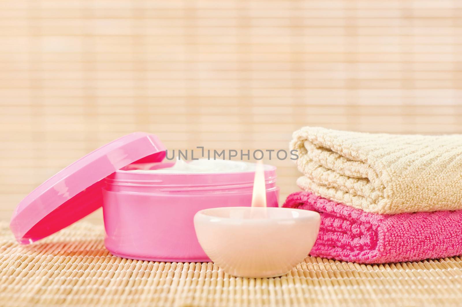 Pink and light brown composition of cream, towels and candle