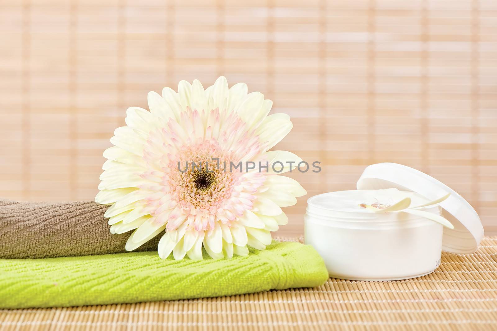 Fresh flower on top of two towels and skin care product
