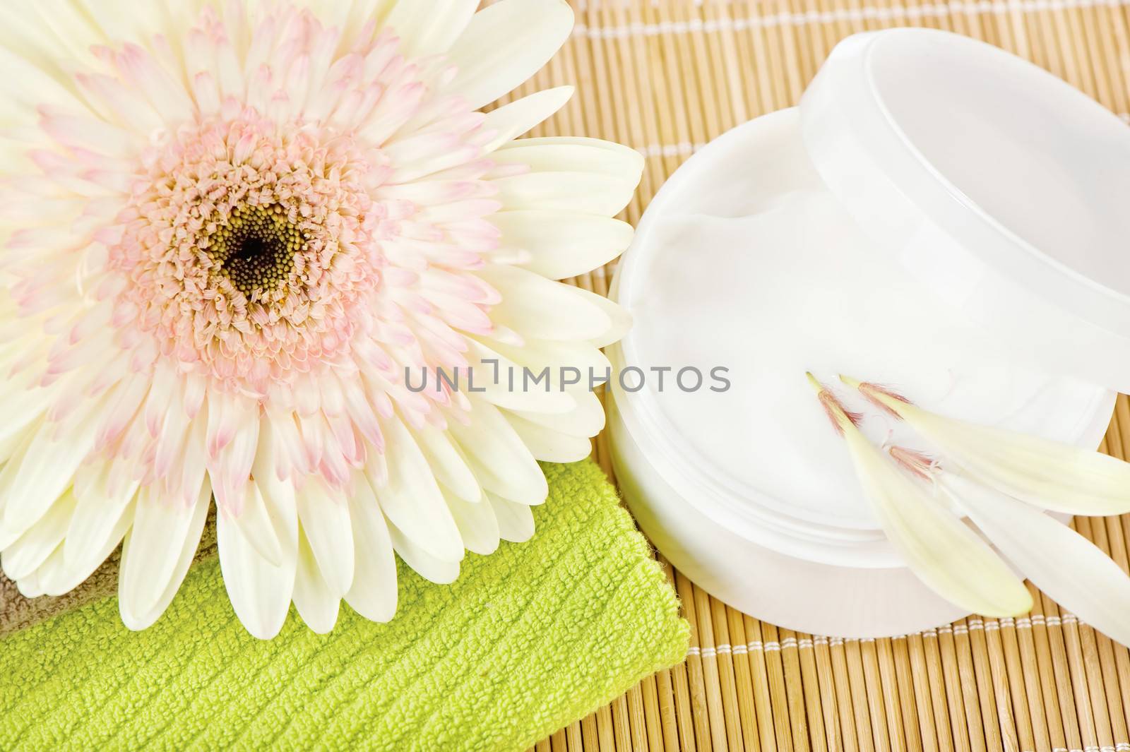 Beautiful flower on top of green towel with skin care product