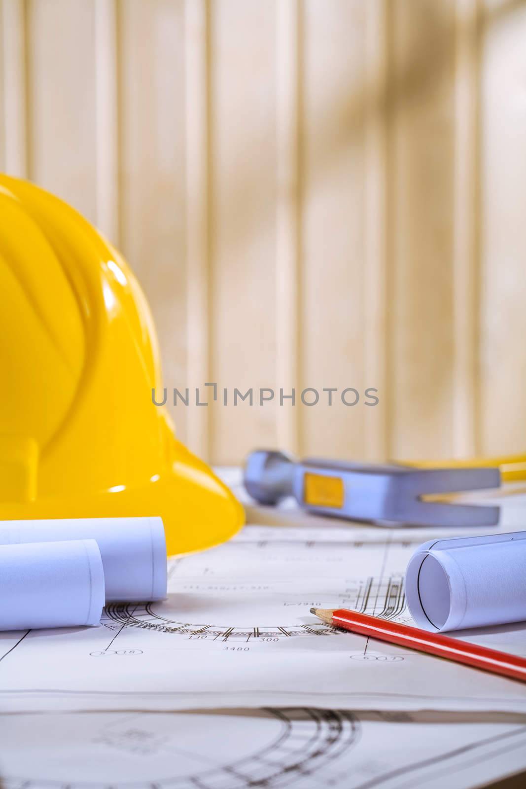helmet pencil and hammer on blueprints