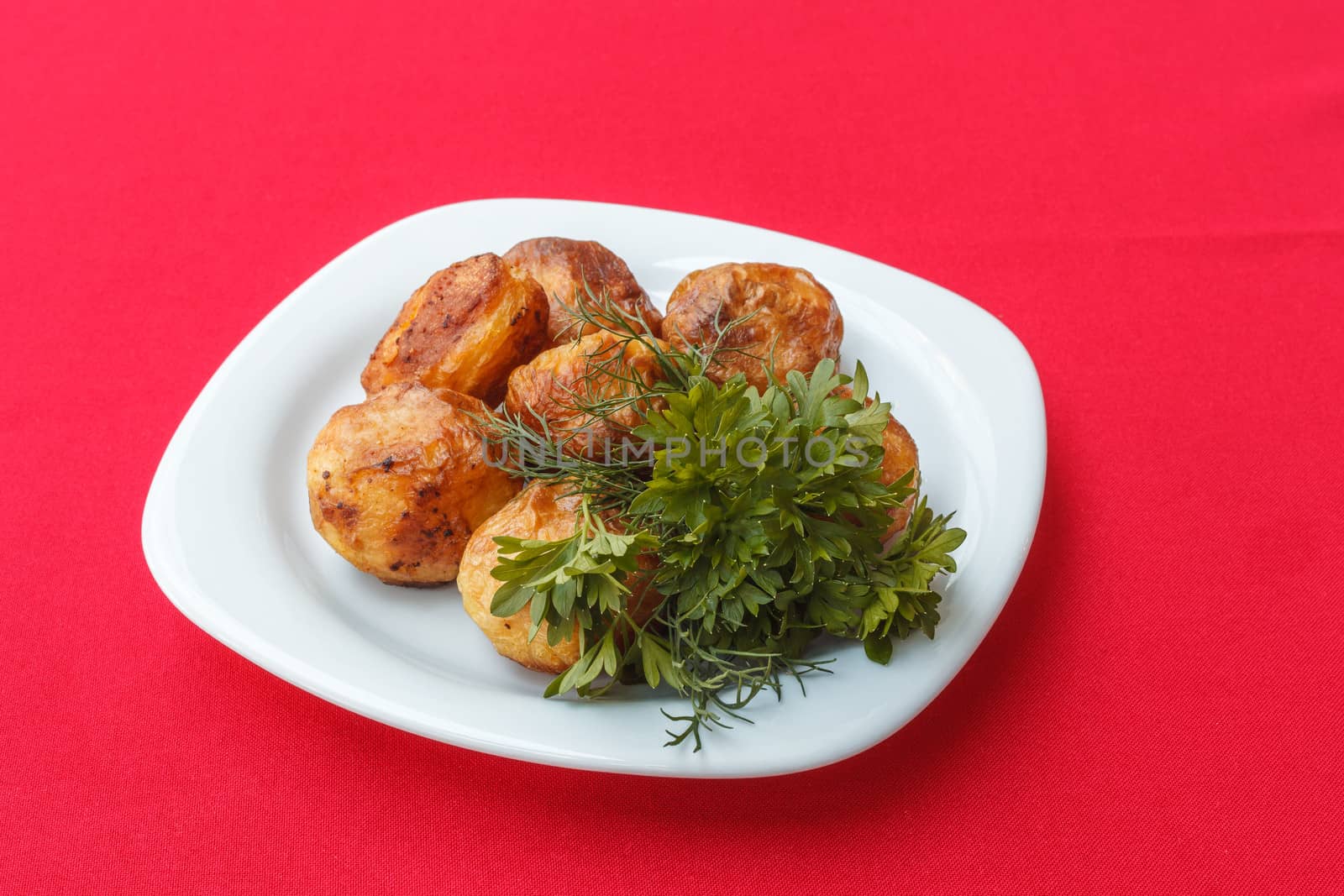 Baked potato with dill and parsley on red background