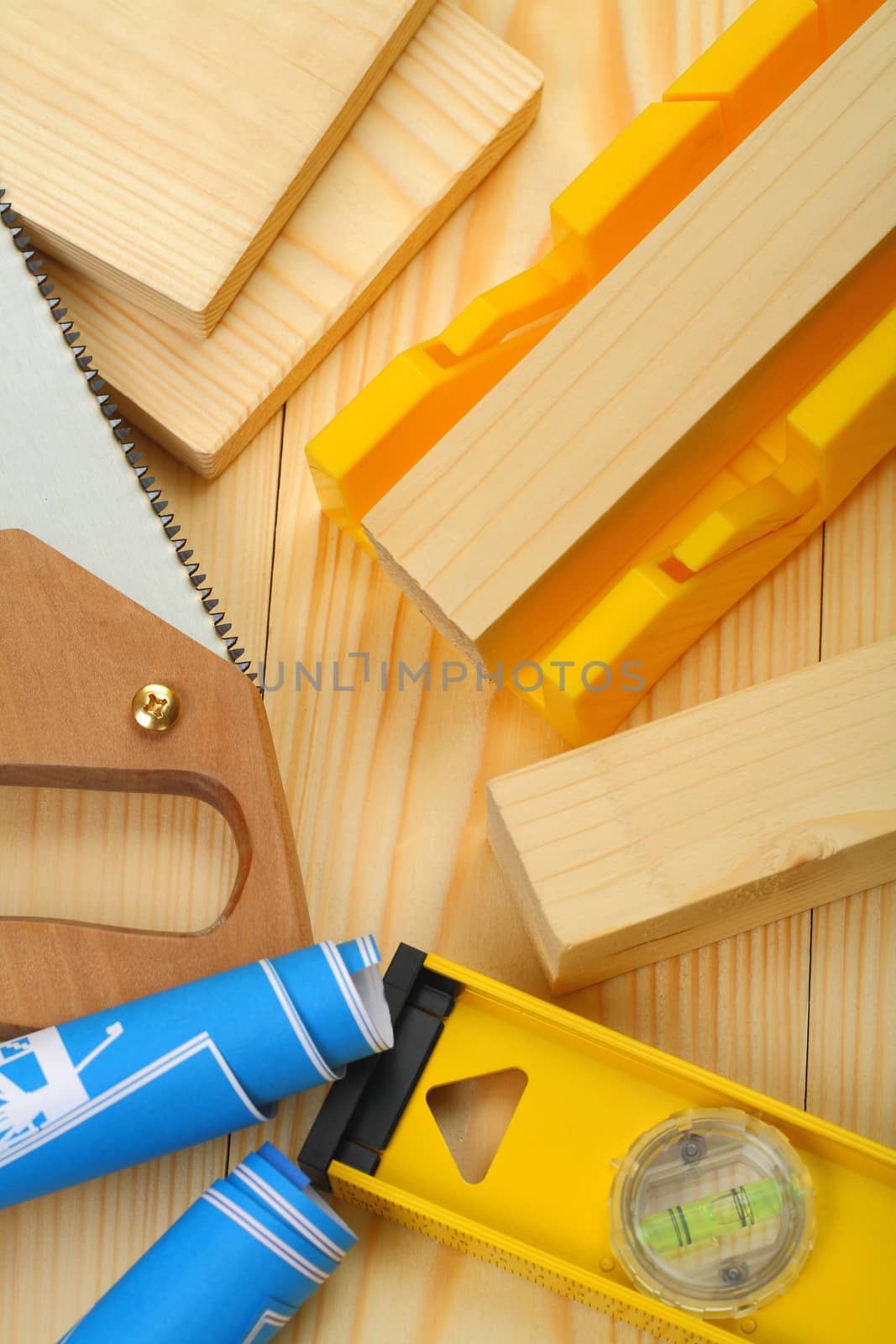 somposition of saw, timber, blueprints, level on wooden boards