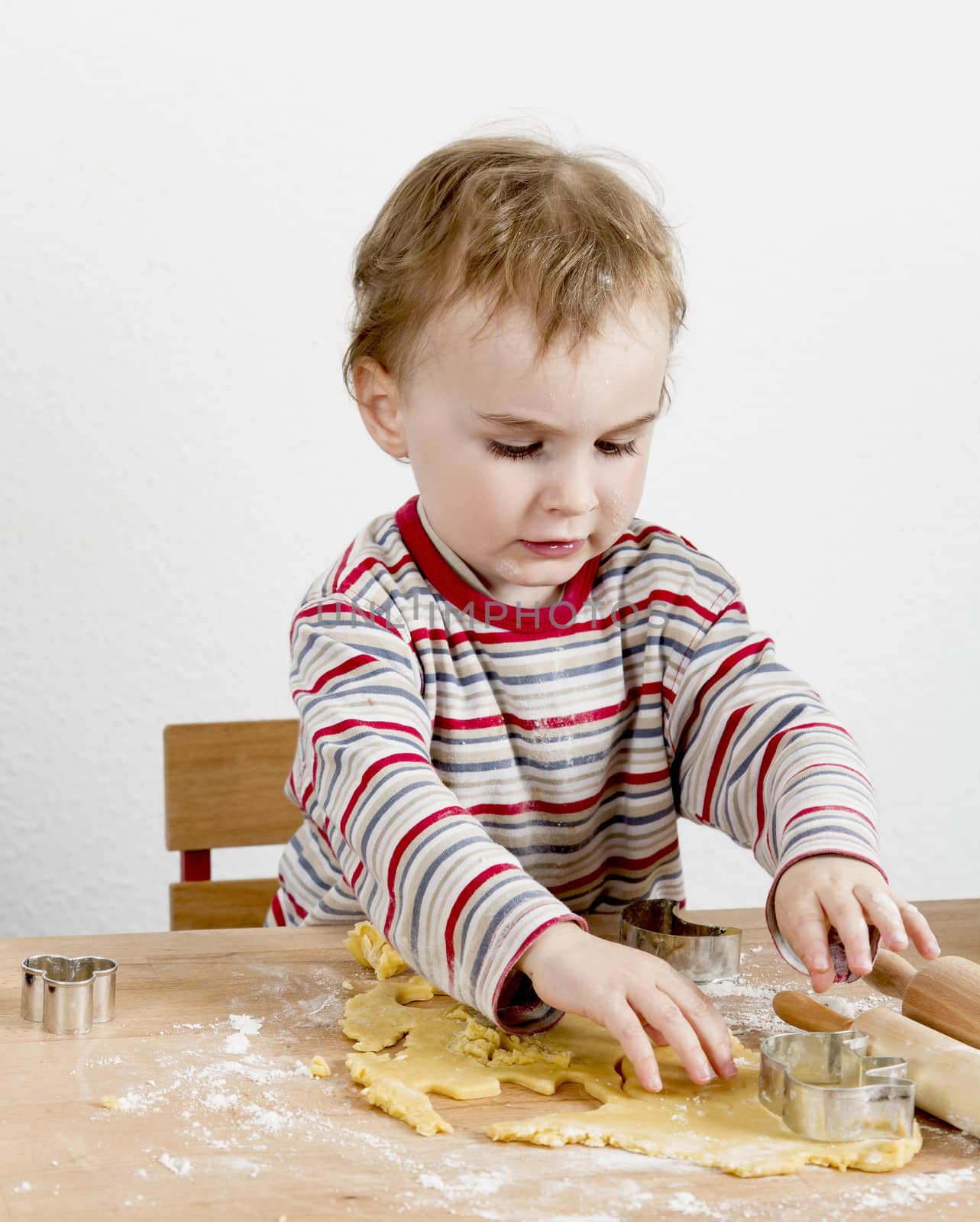 child at wooden desk making cookies. vertical image