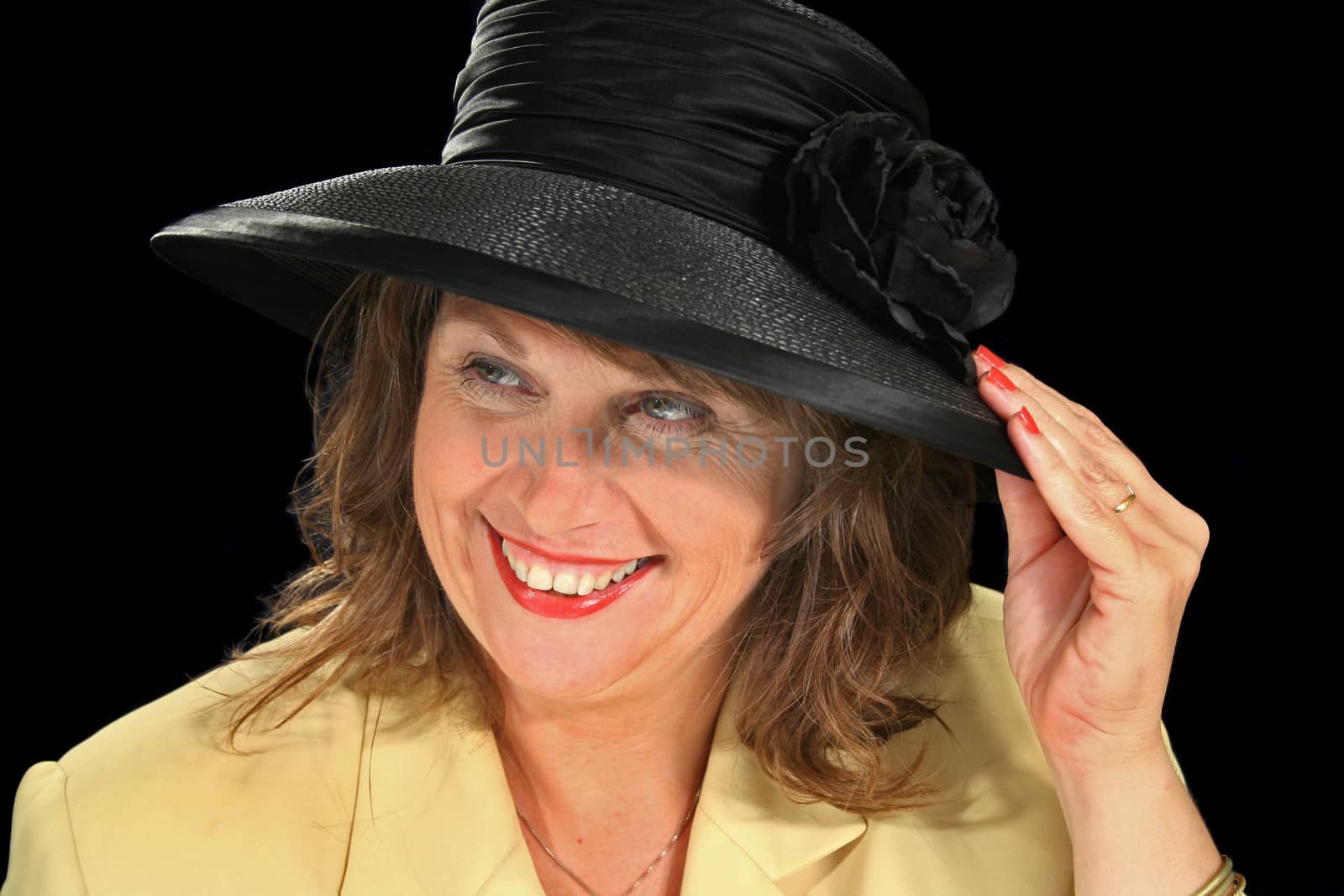 Middle aged female smiling and holding her black hat.