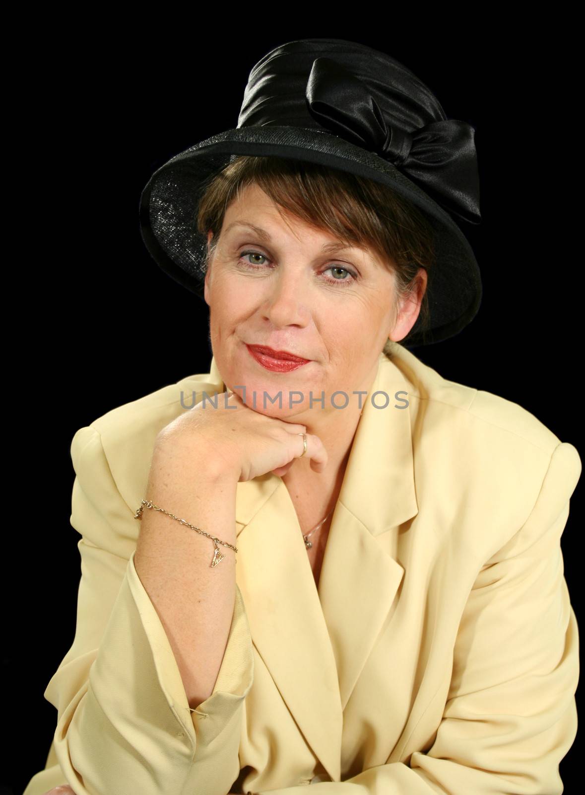 Pensive middle aged woman in a black hat looking to camera.