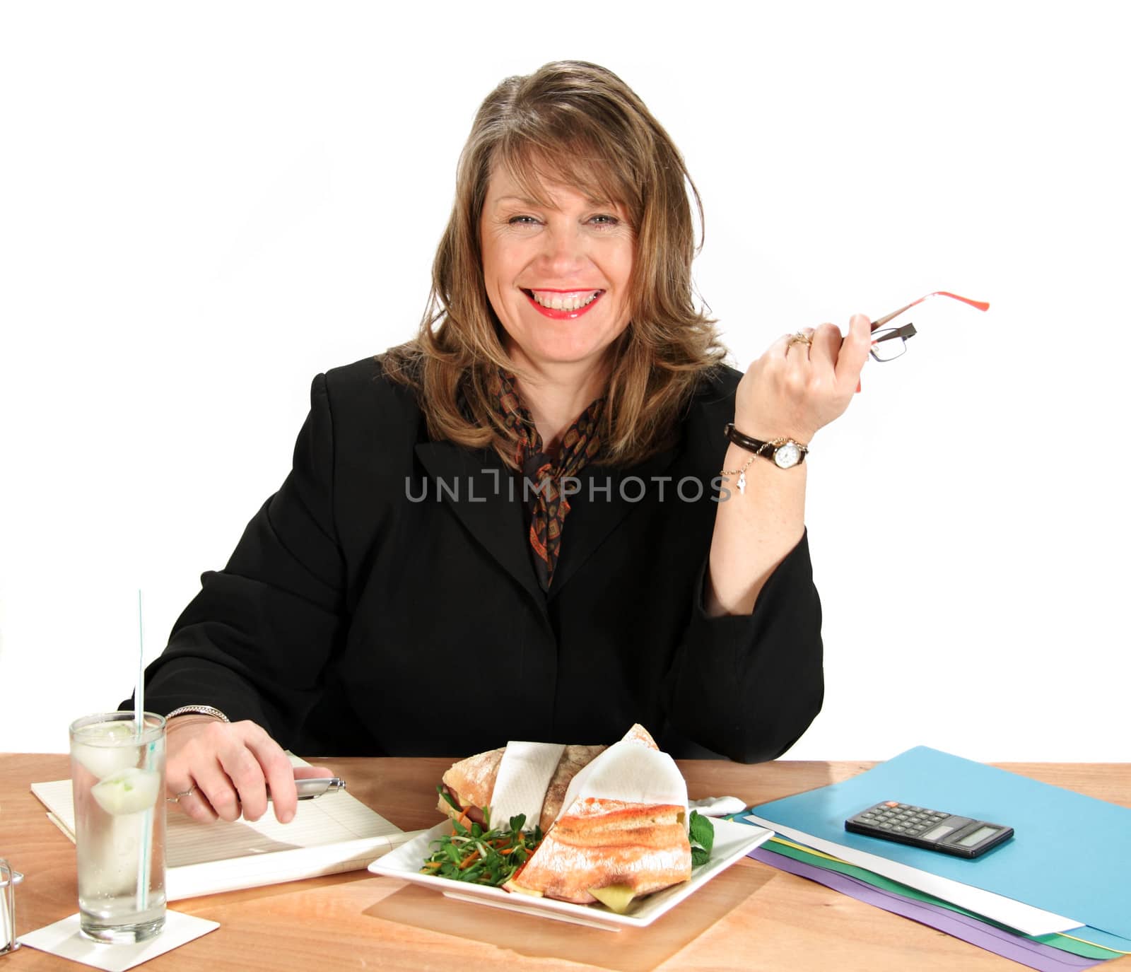 Middle aged businesswoman eats lunch while still working at her desk.