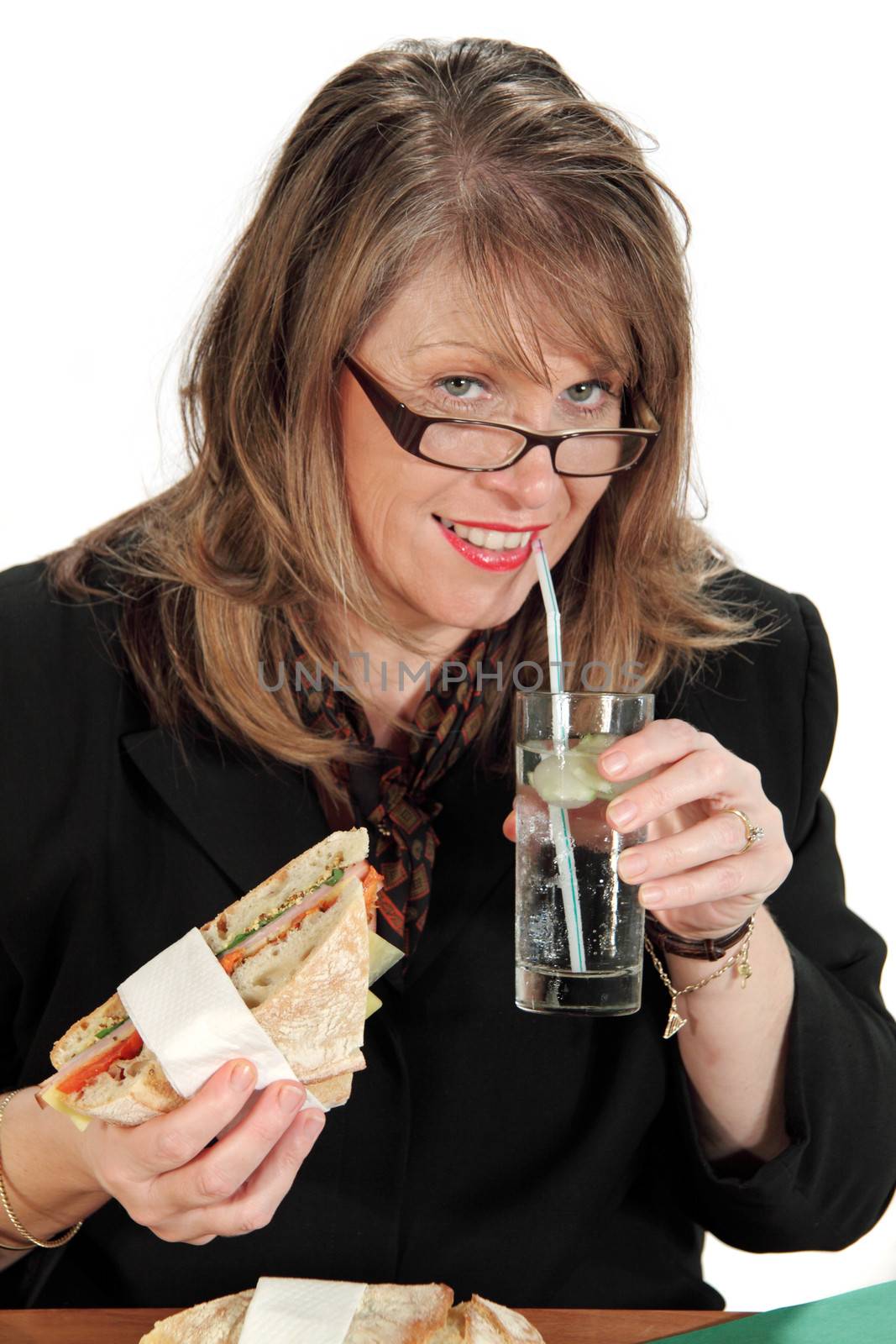 Middle aged businesswoman eats lunch while still working at her desk.