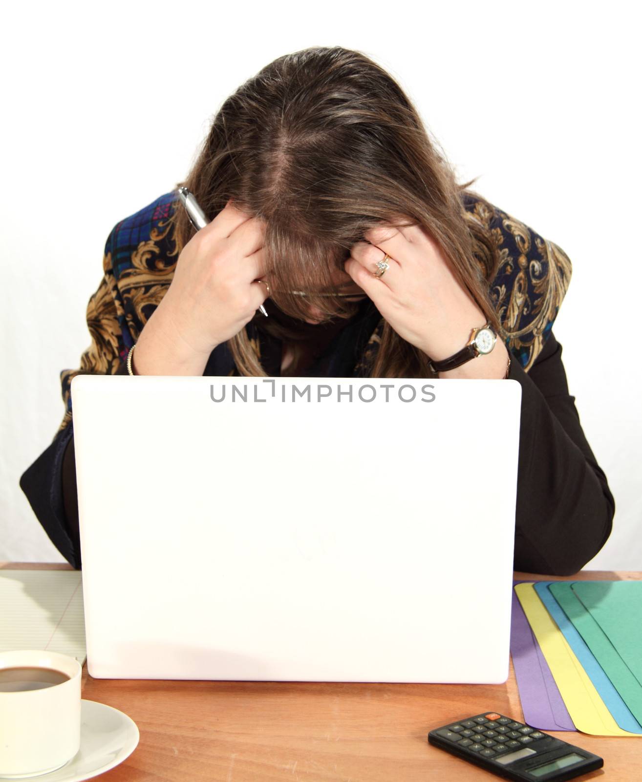 Dejected middle aged businesswoman with head in hands in front of laptop.