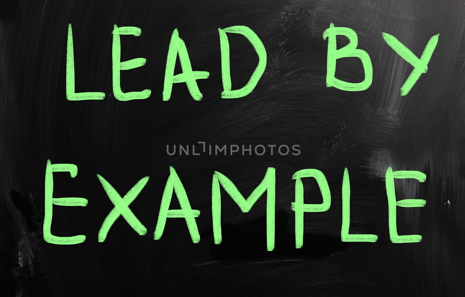 "Lead by example" handwritten with white chalk on a blackboard