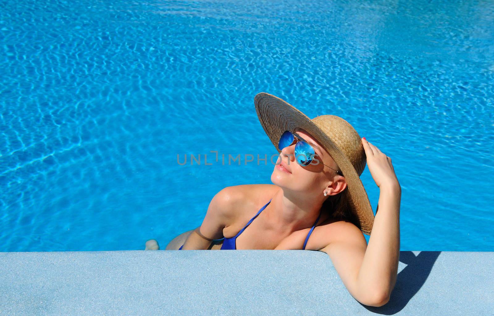 Woman in hat relaxing at the pool 