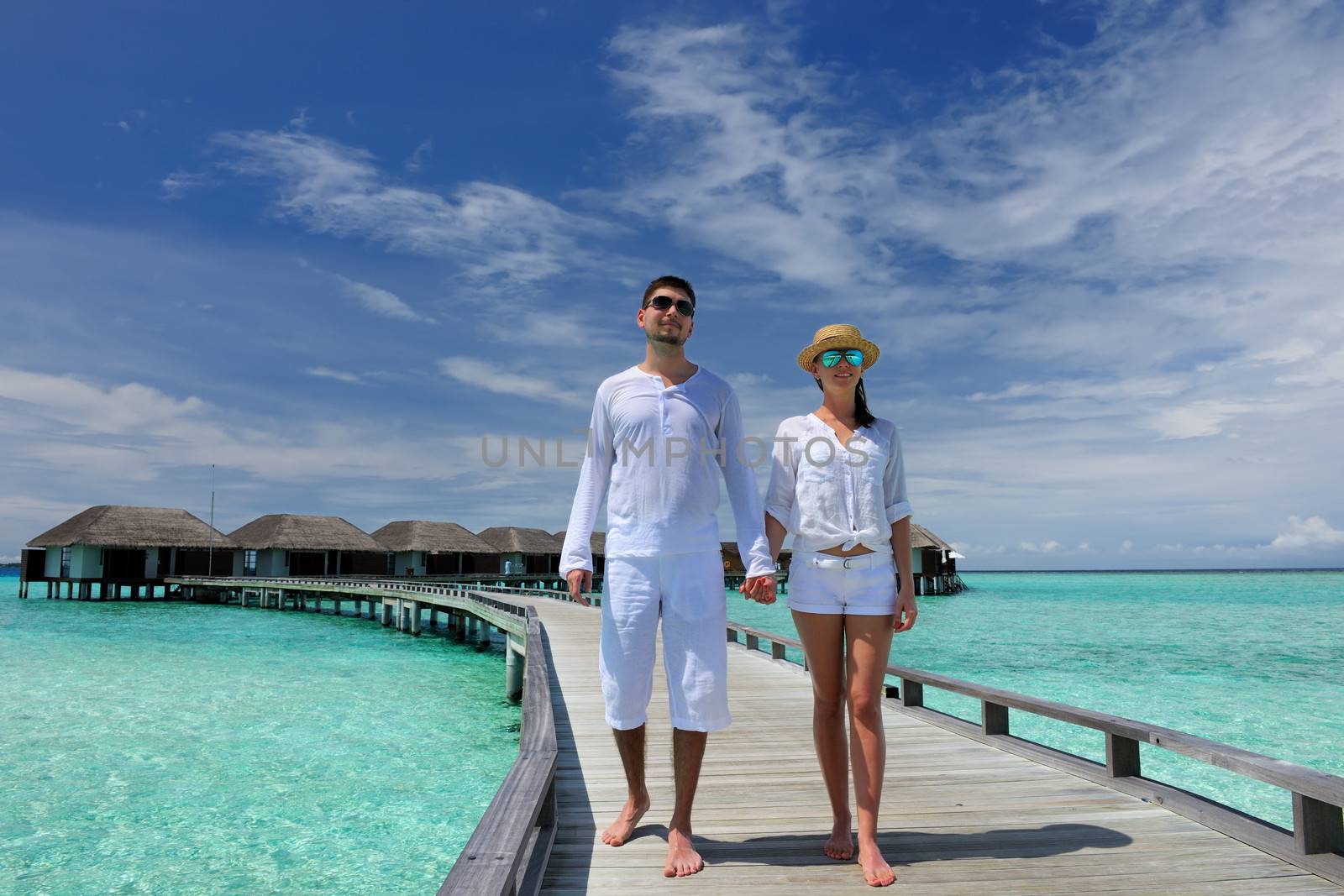 Couple on a tropical beach jetty at Maldives