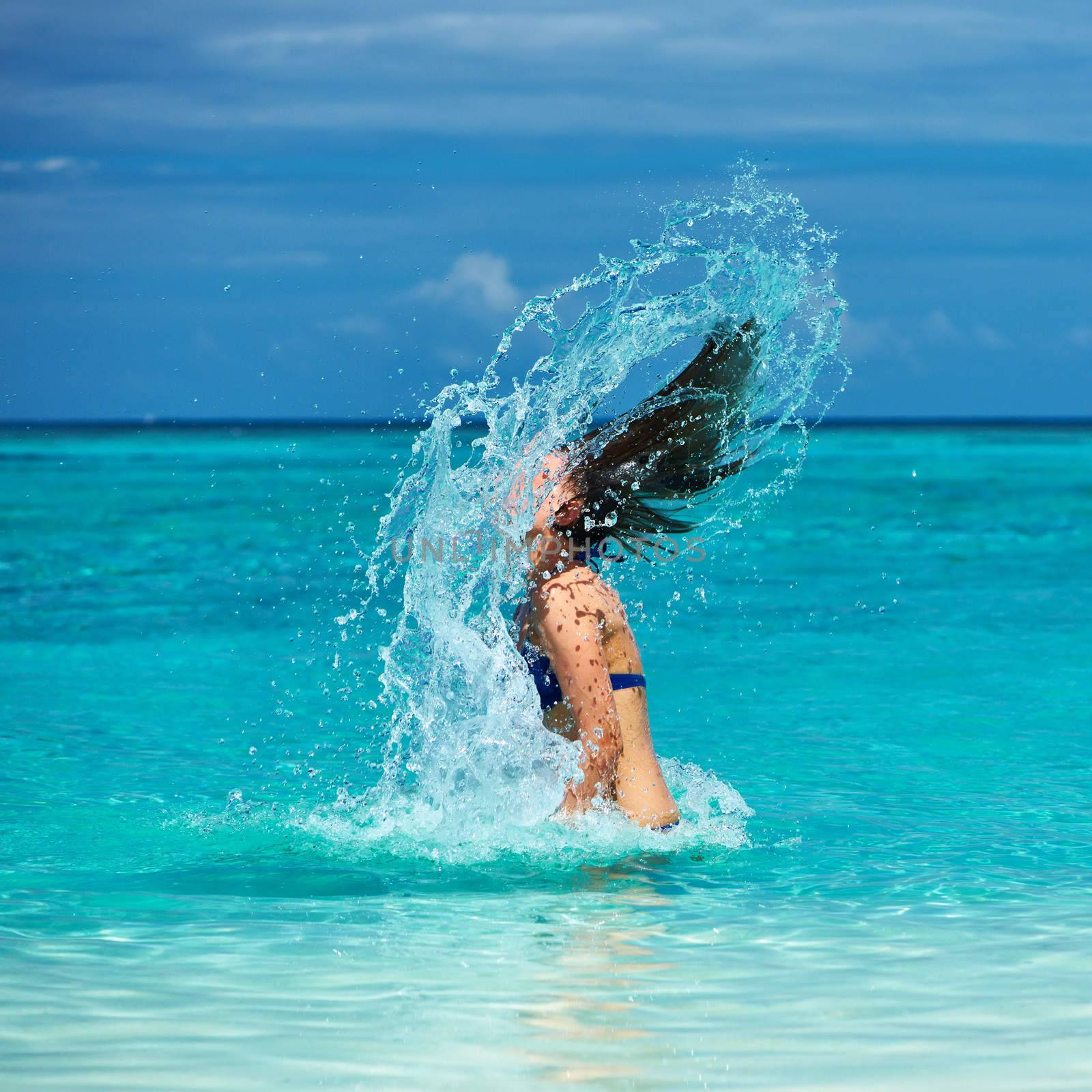 Woman splashing water with hair in the ocean by haveseen