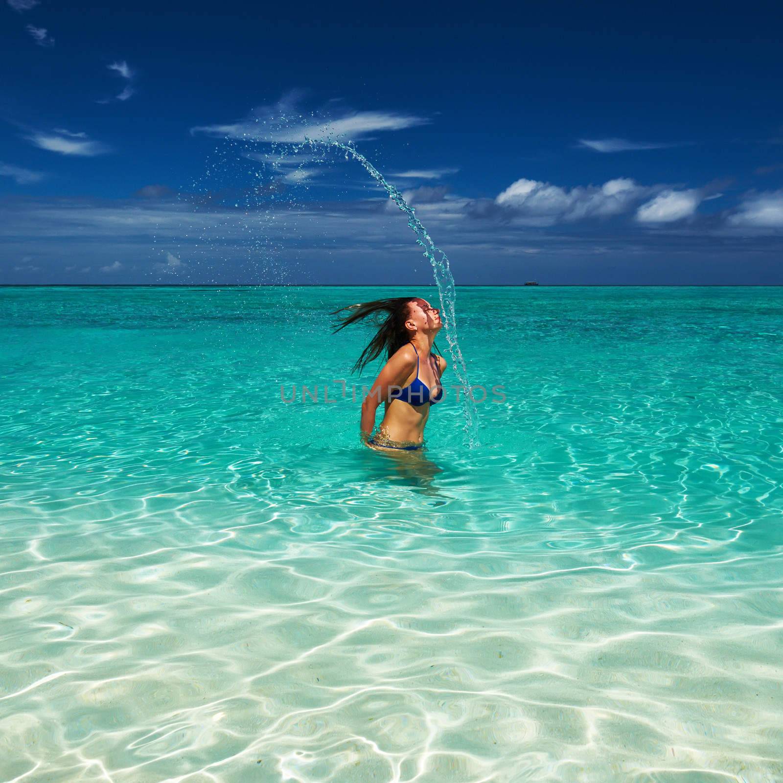 Woman splashing water with her hair in the ocean