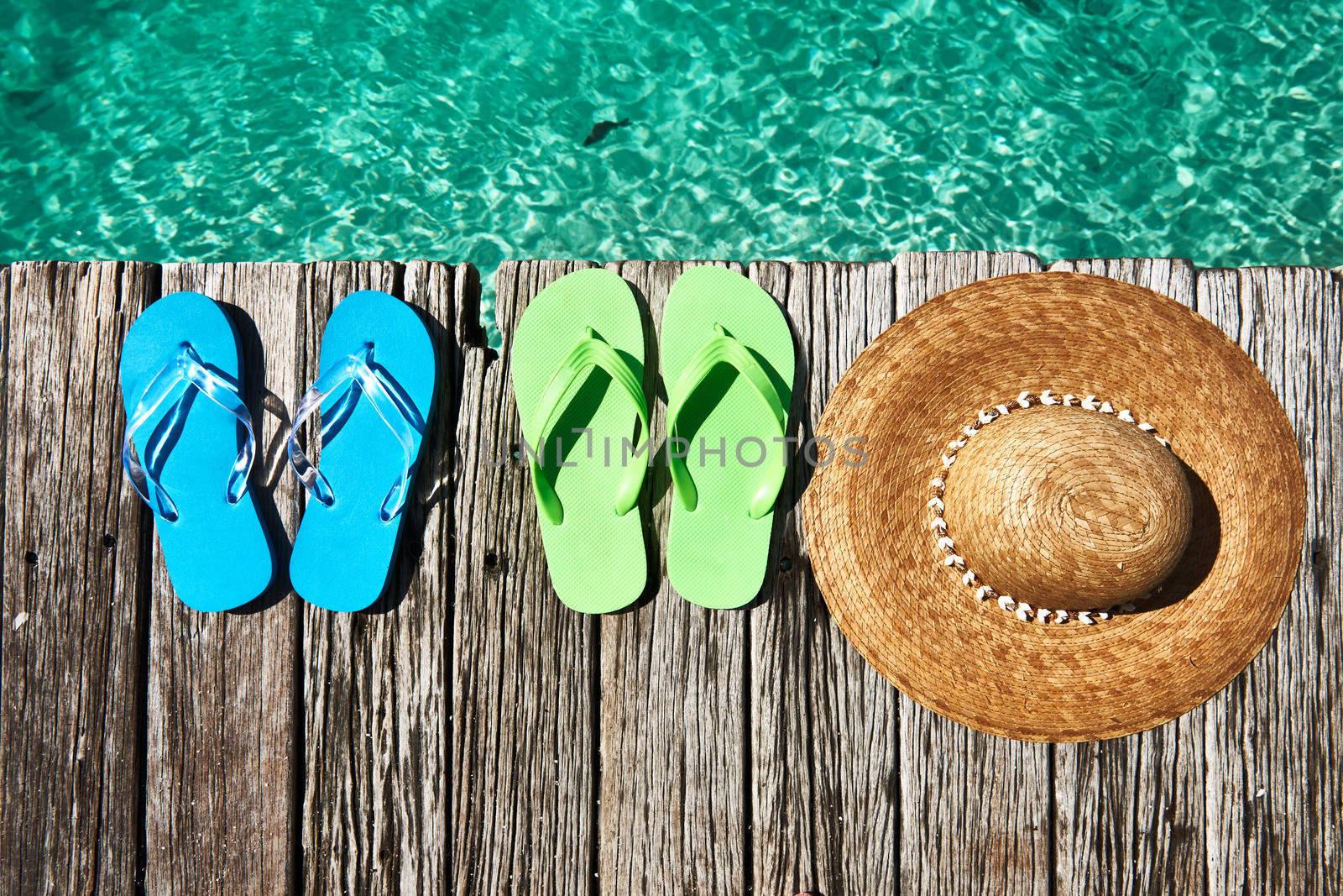 Slippers and hat at jetty by the sea