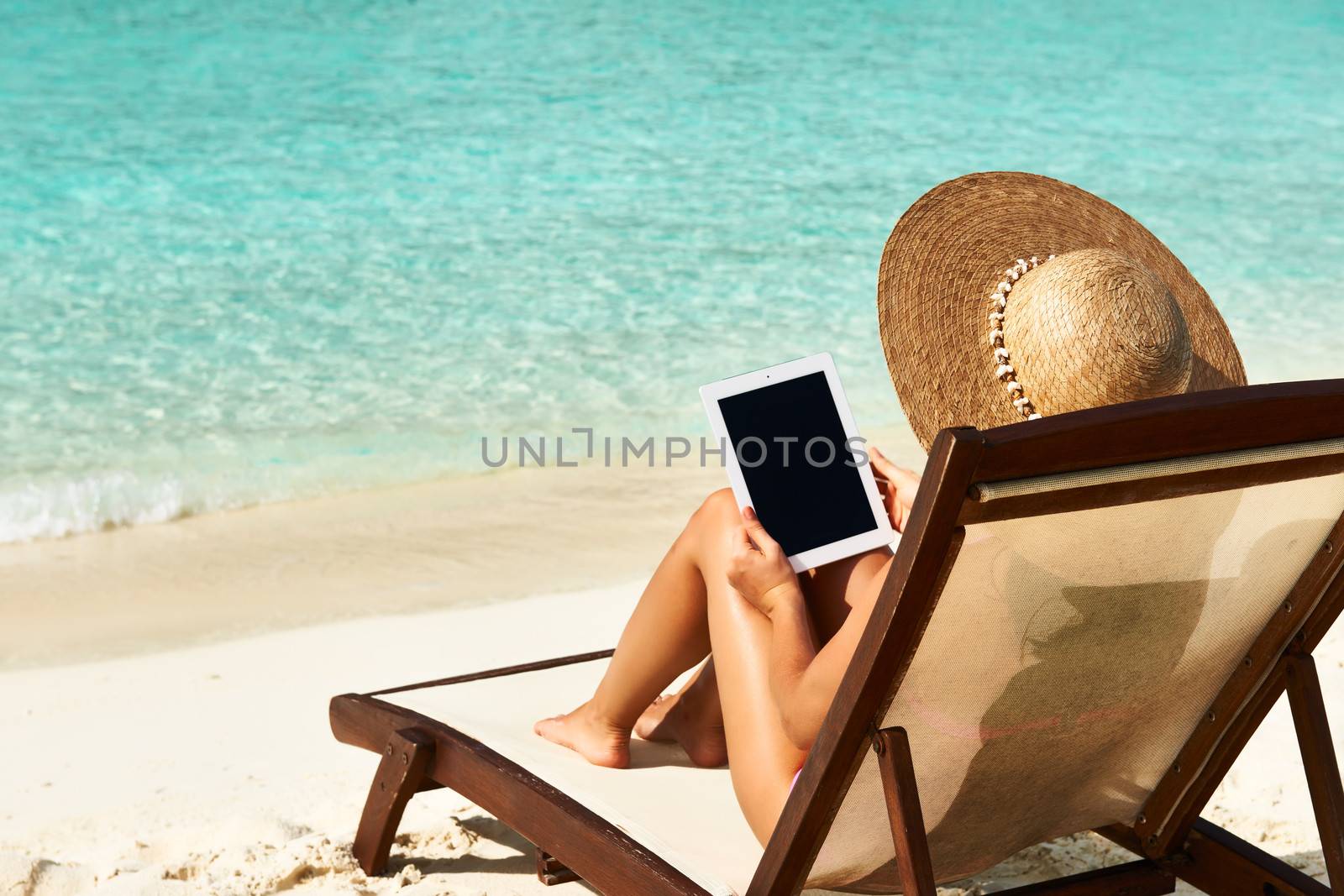 Young woman in hat with tablet pc at the beach