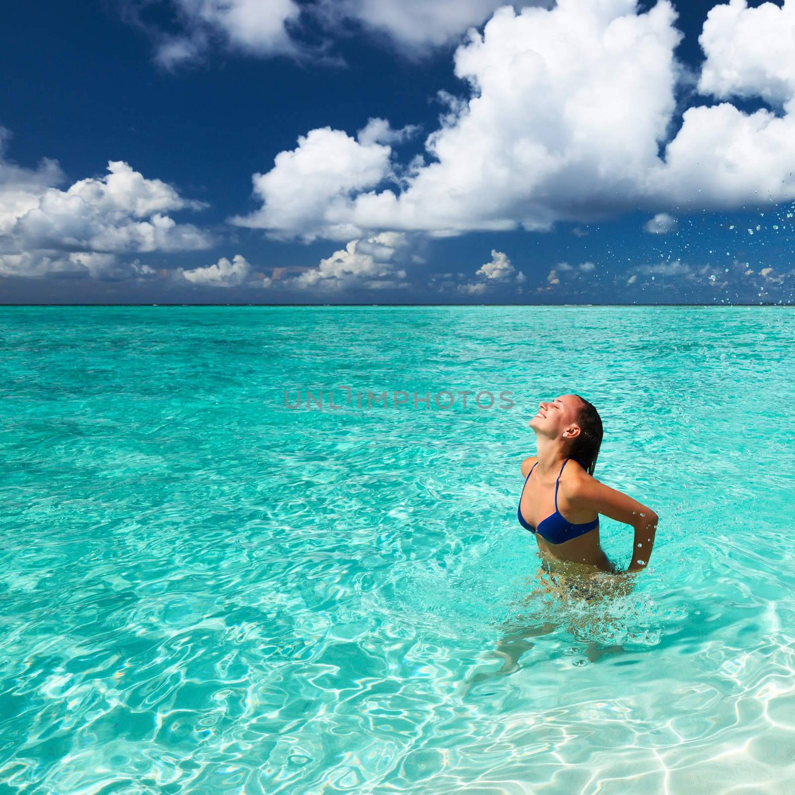 Woman splashing water with hair in the ocean by haveseen