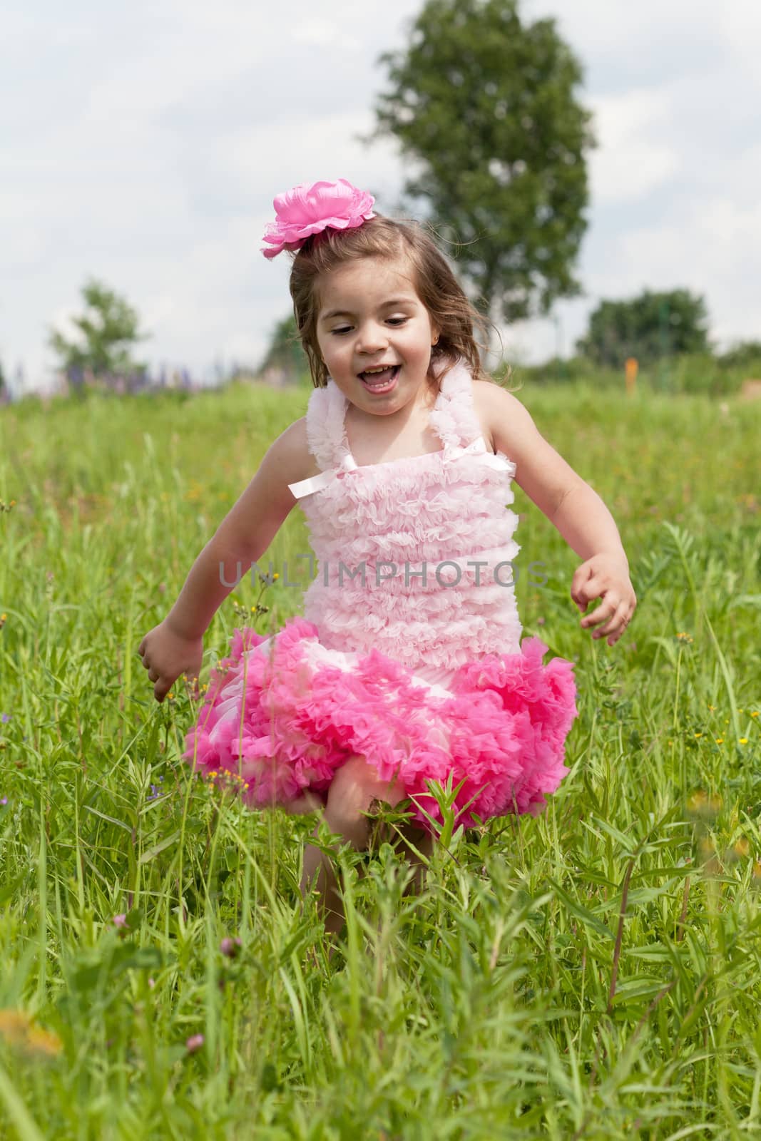 little girl in a pink dress runs on a grass