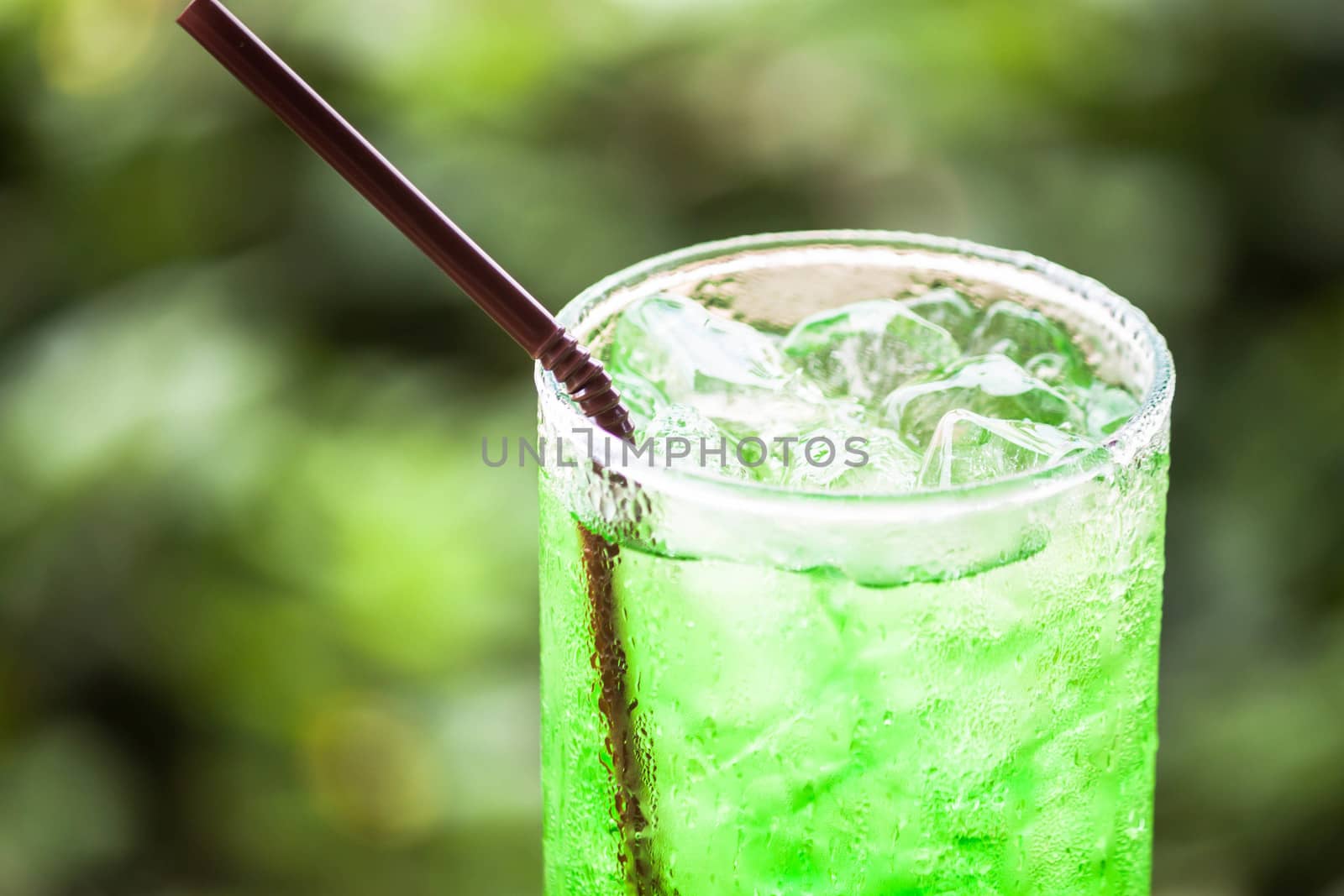 Glass of iced green drink with straw