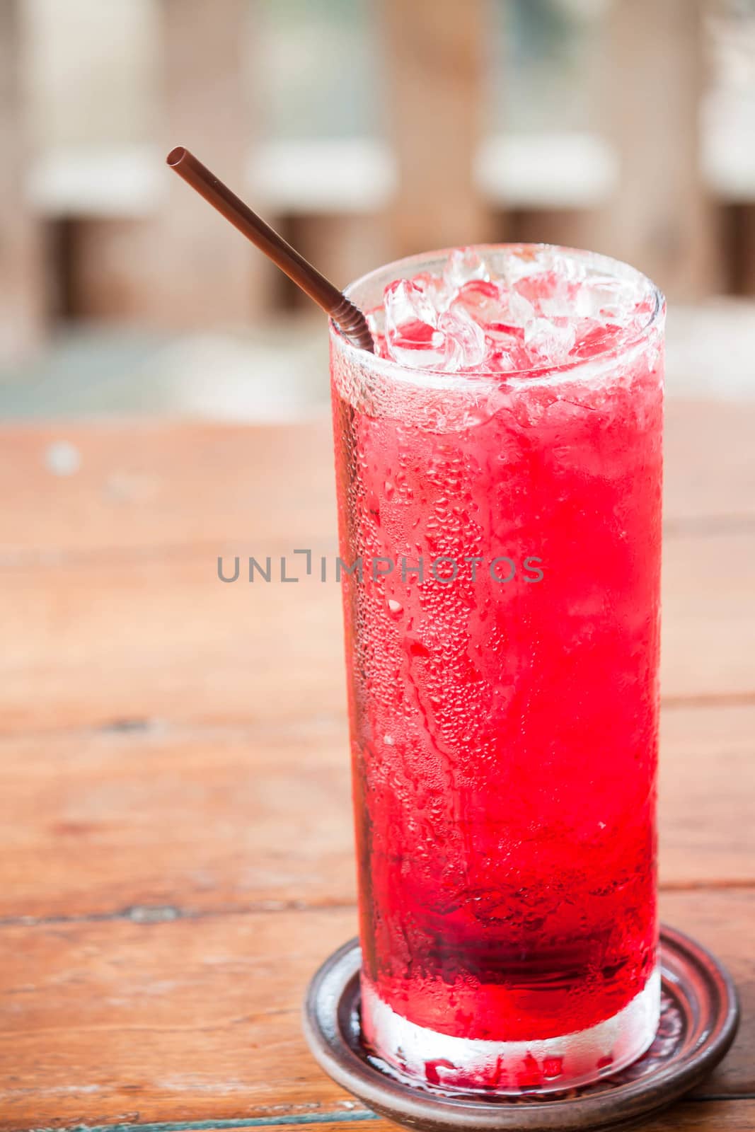 Glass of iced red drink with straw  by punsayaporn