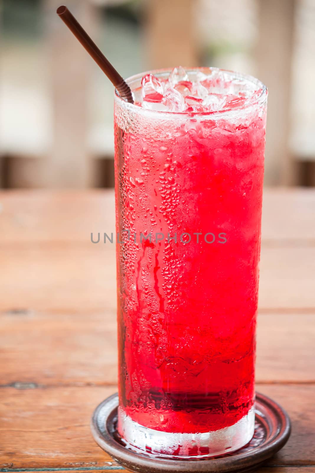 Glass of cold red drink with straw  by punsayaporn