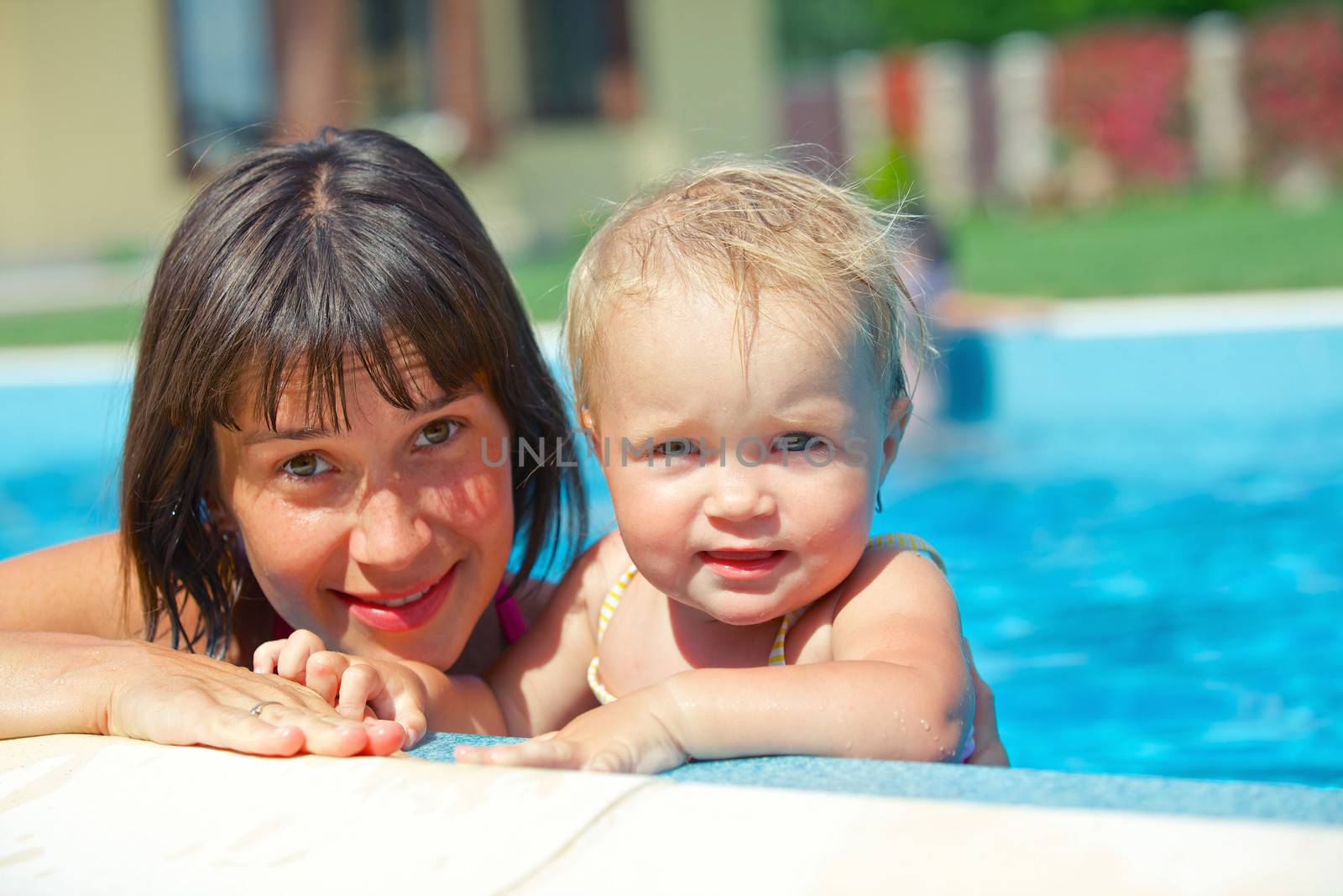 Summer vacation. Pretty baby girl with her mother in swimming pool outdoors