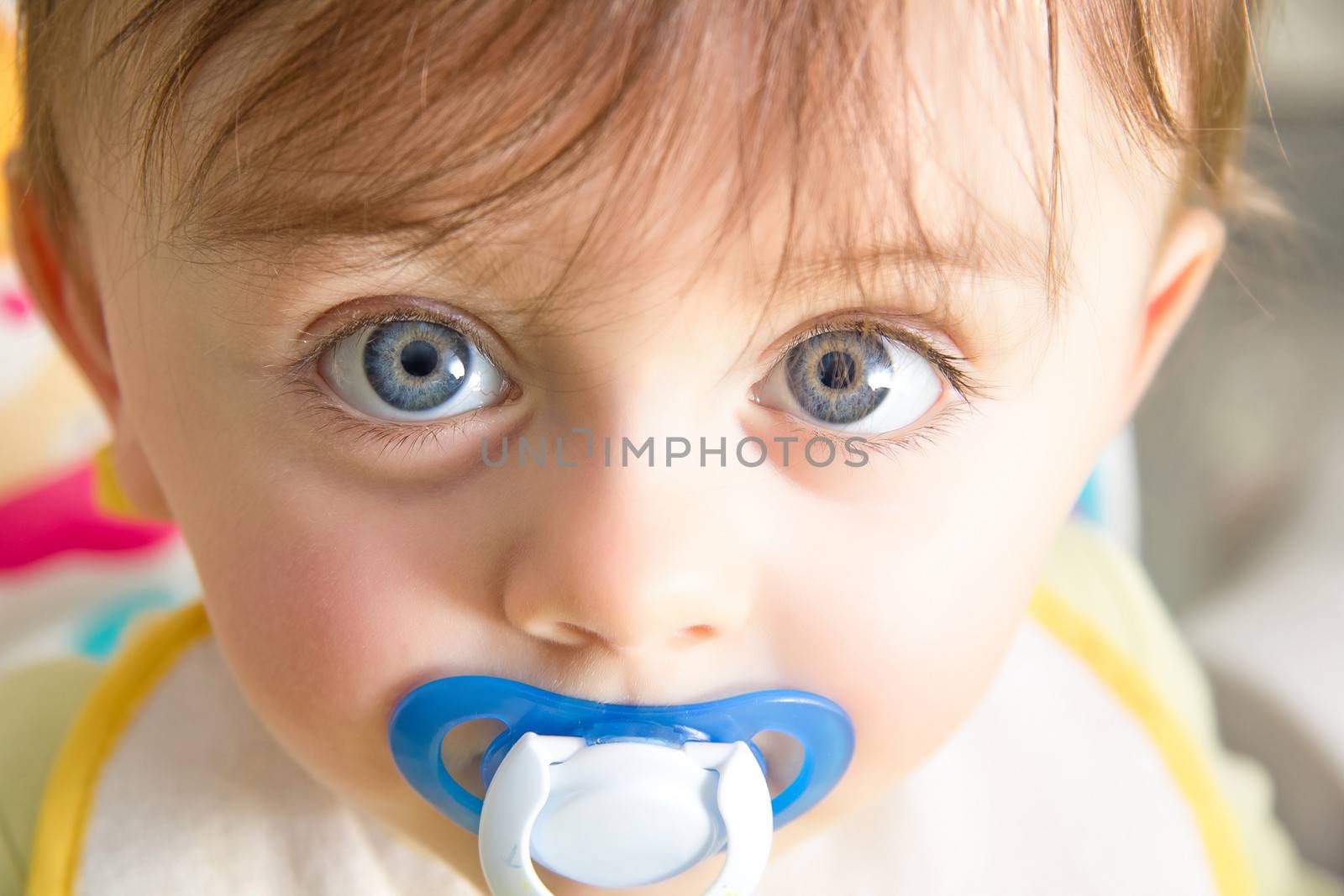 Cute baby with pacifier looking at the camera