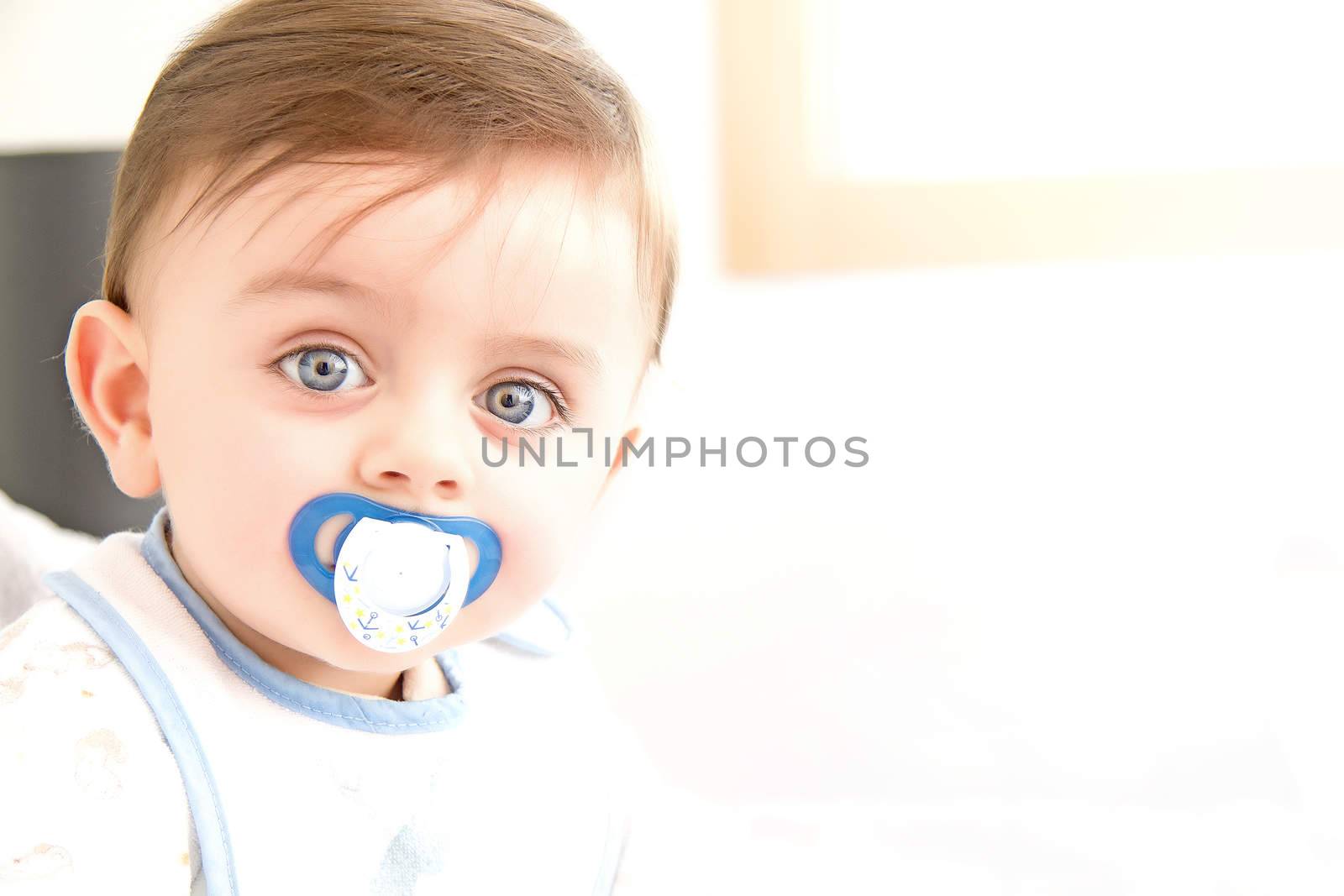 Cute baby with pacifier looking at the camera