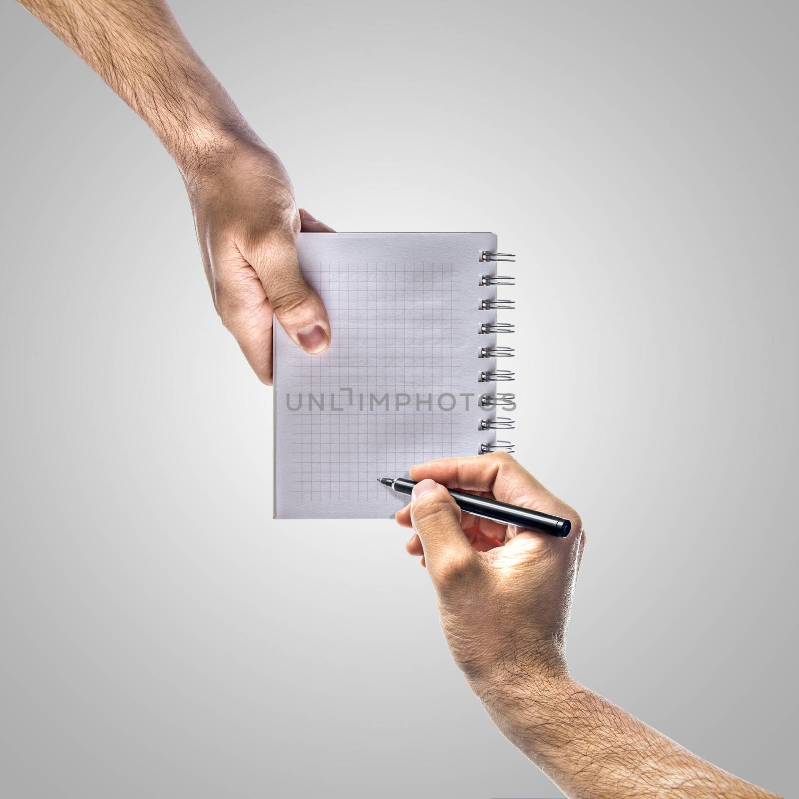 Hand holding notebook and another is taking notes