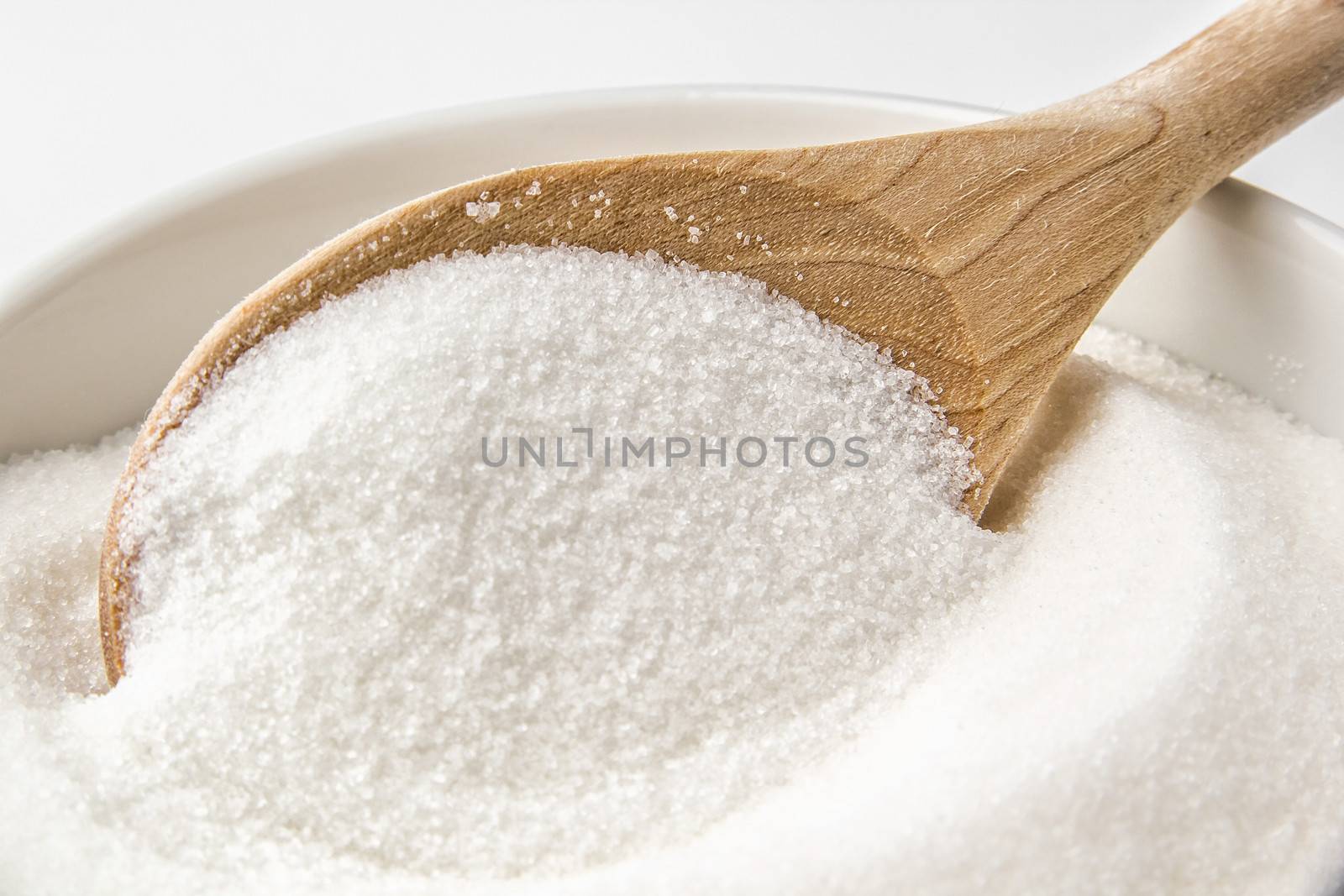 Wooden spoon and a bowl fill with sugar