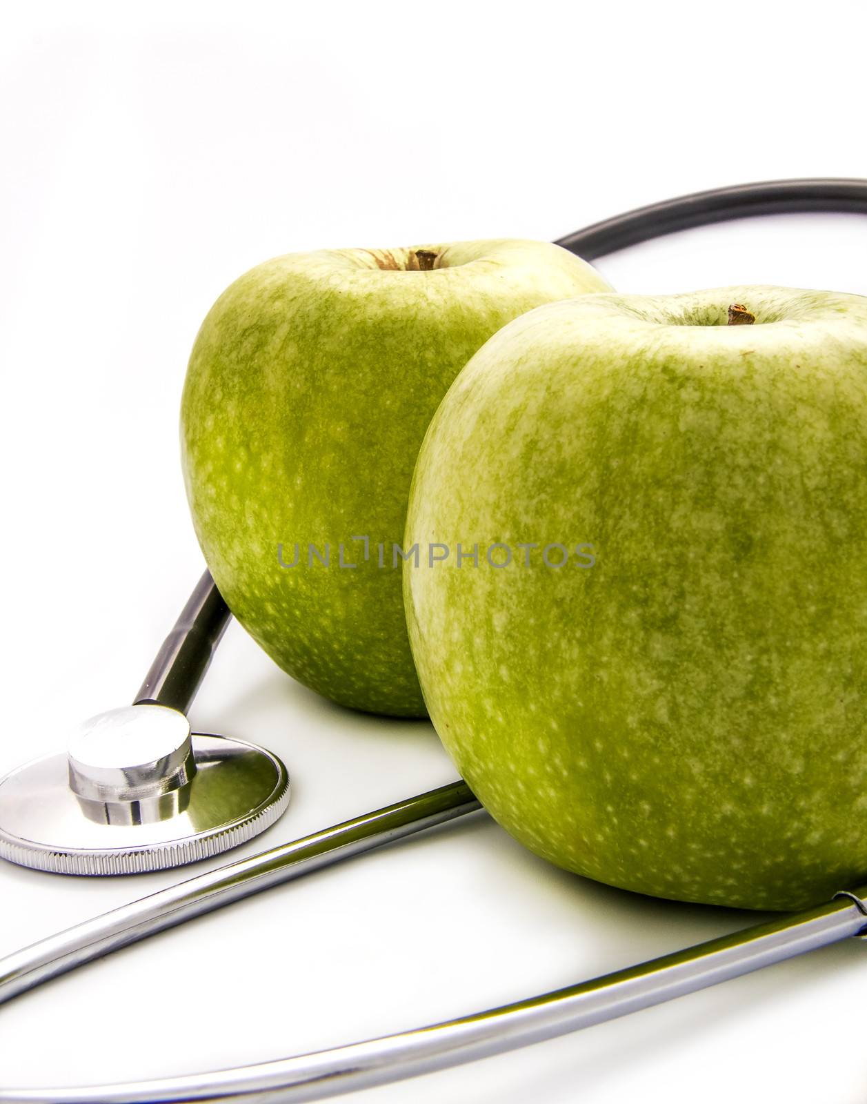 Green apples and a stethoscope on white background