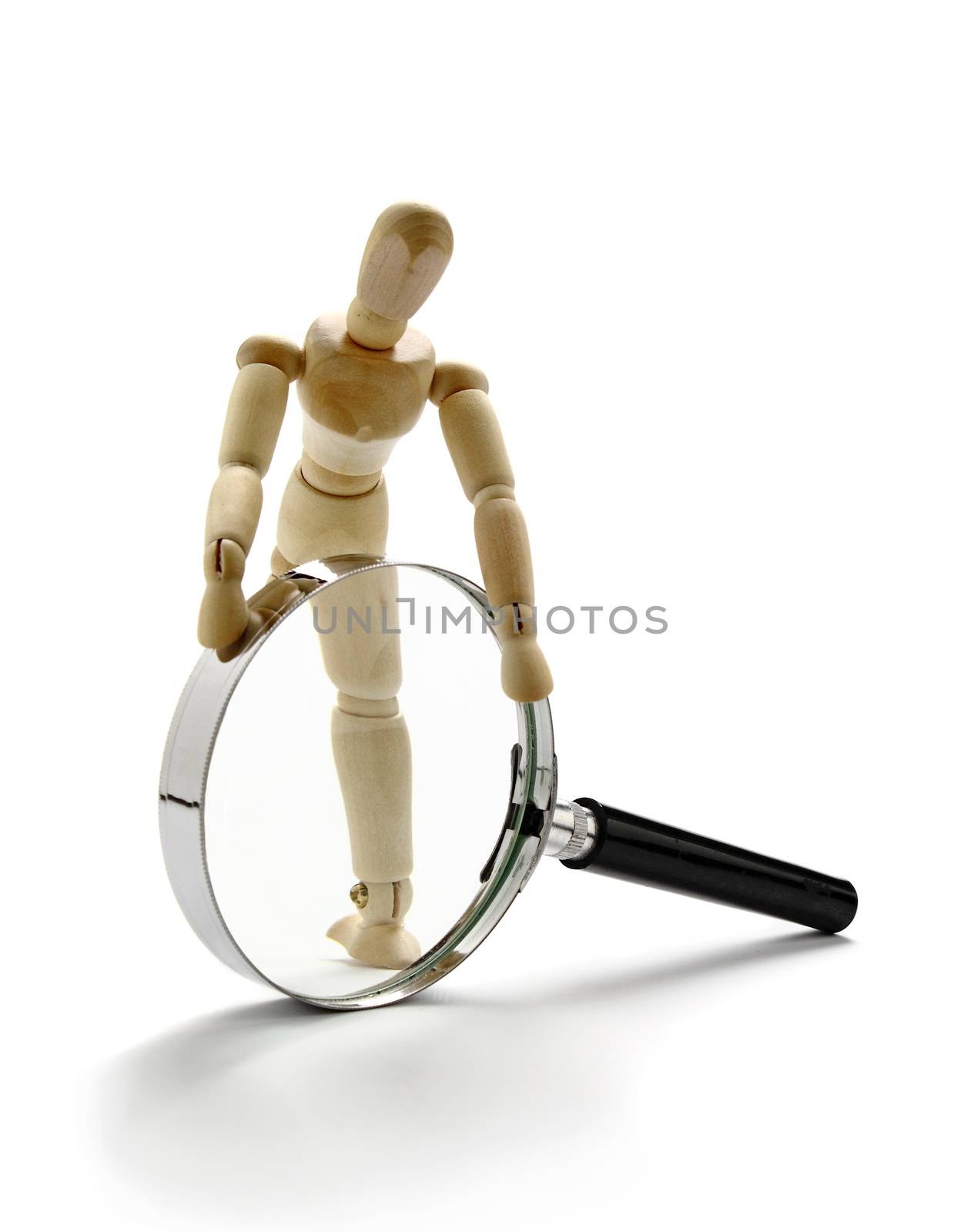 Wooden manikin and a magnification glass on white background