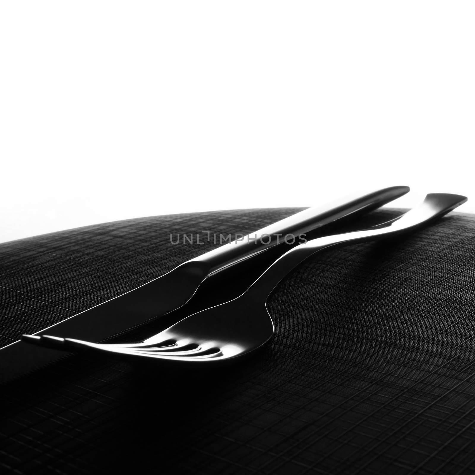 Silver knife and fork on black surface