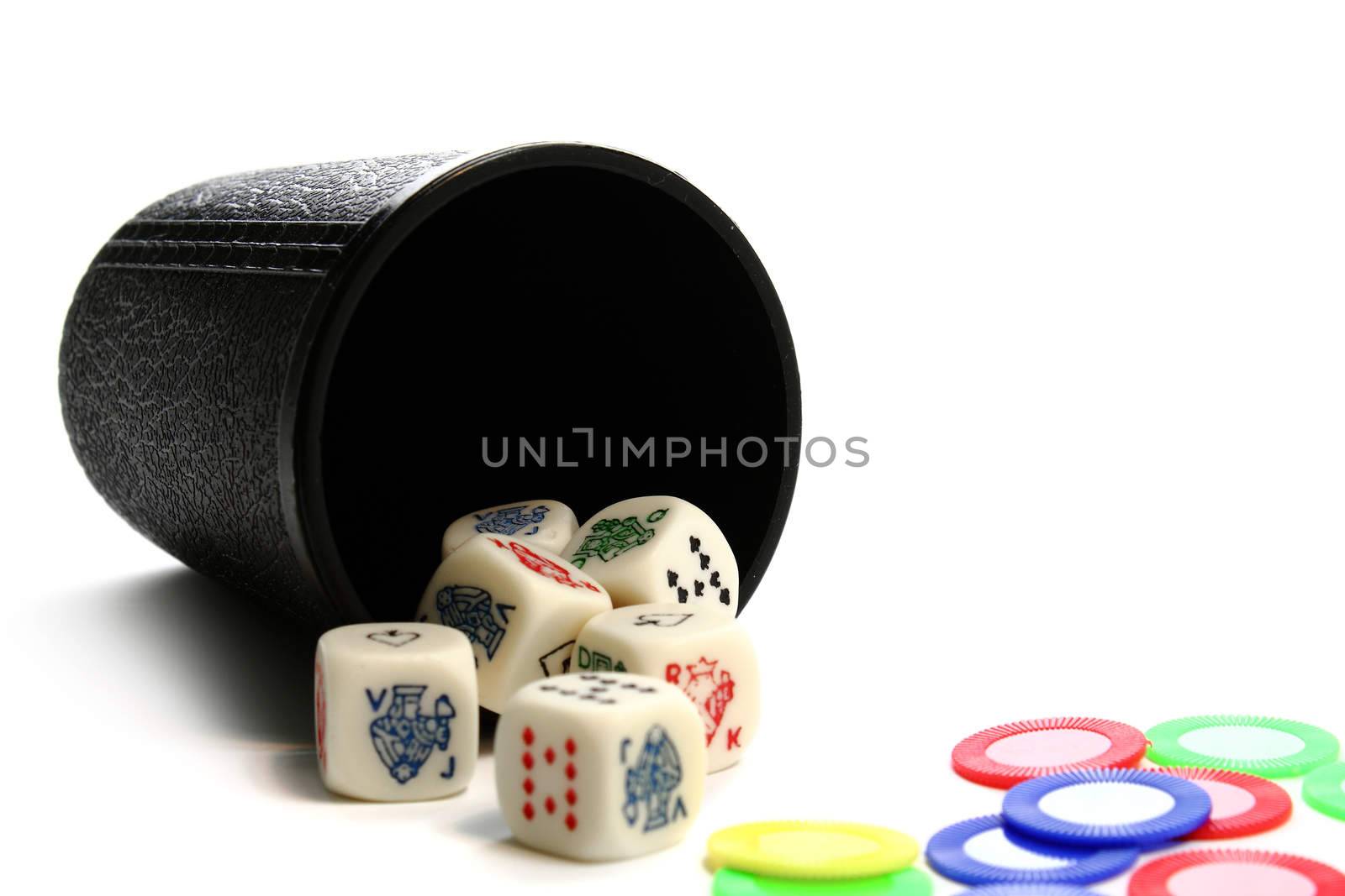 A cup six dice and colorful chips on white