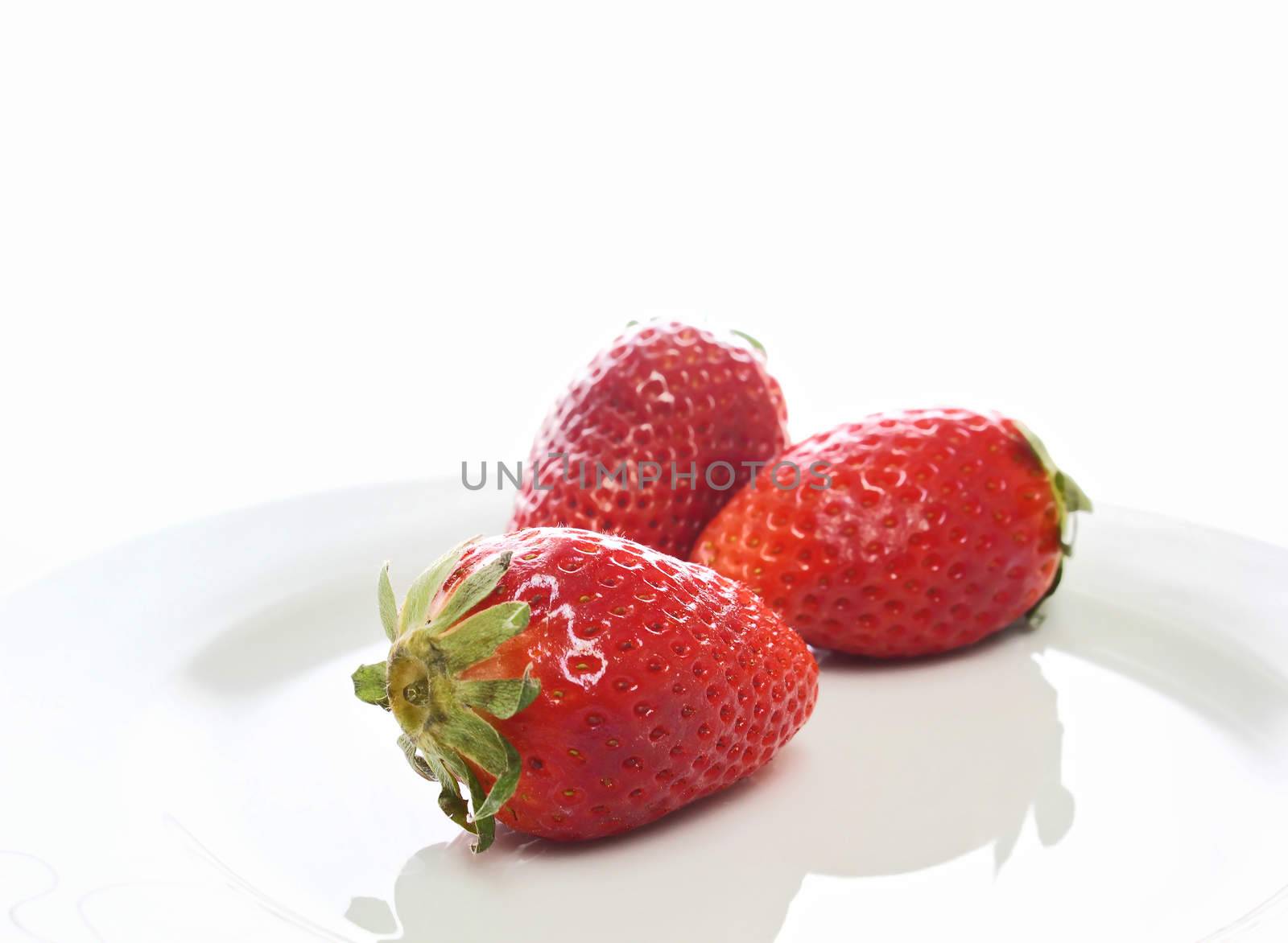 Three strawberries on a white dish
