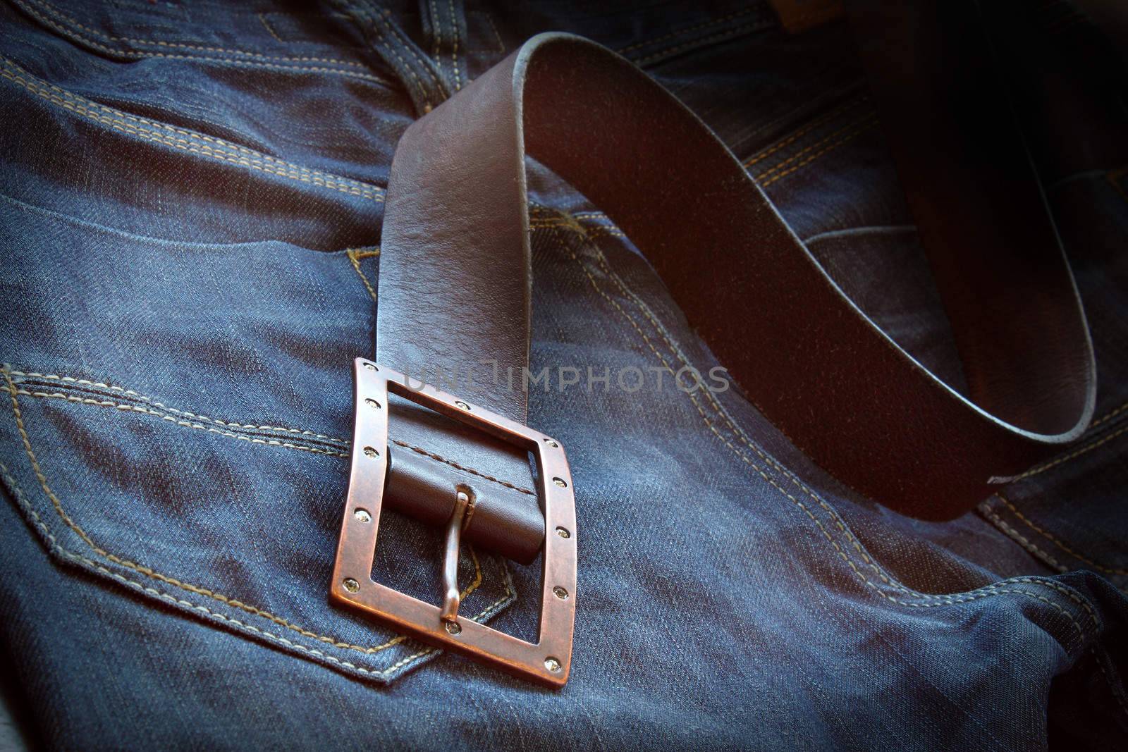 Leather belt over a pair of jeans by dynamicfoto