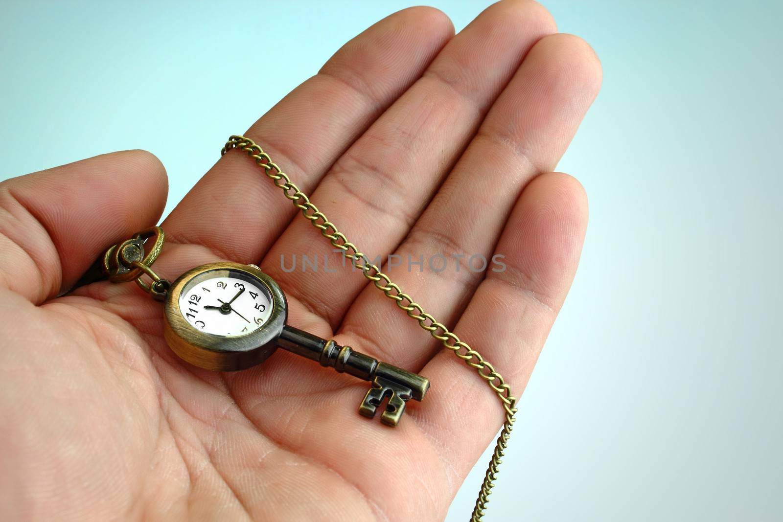 Hand holding a golden key with a built in clock