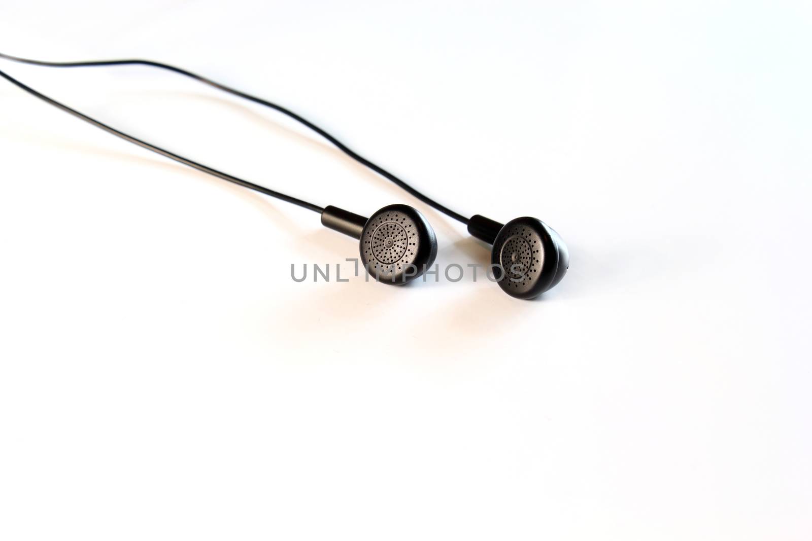 Black earphones on white by dynamicfoto
