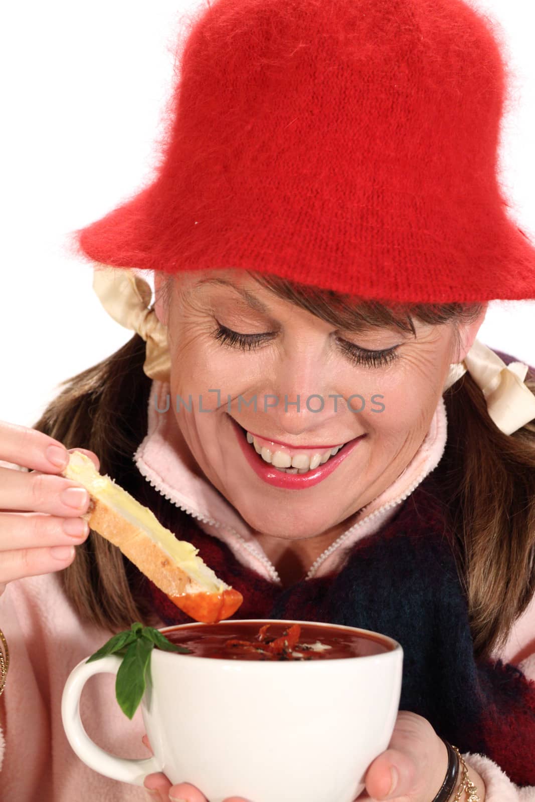 Middle aged woman dipping bread in to tomato soup in winter.