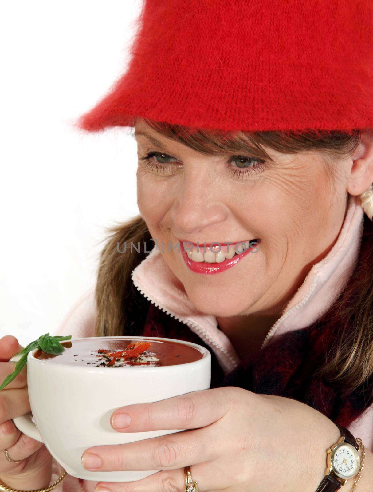 Middle aged woman rugged up for winter holding a hot cup of soup.