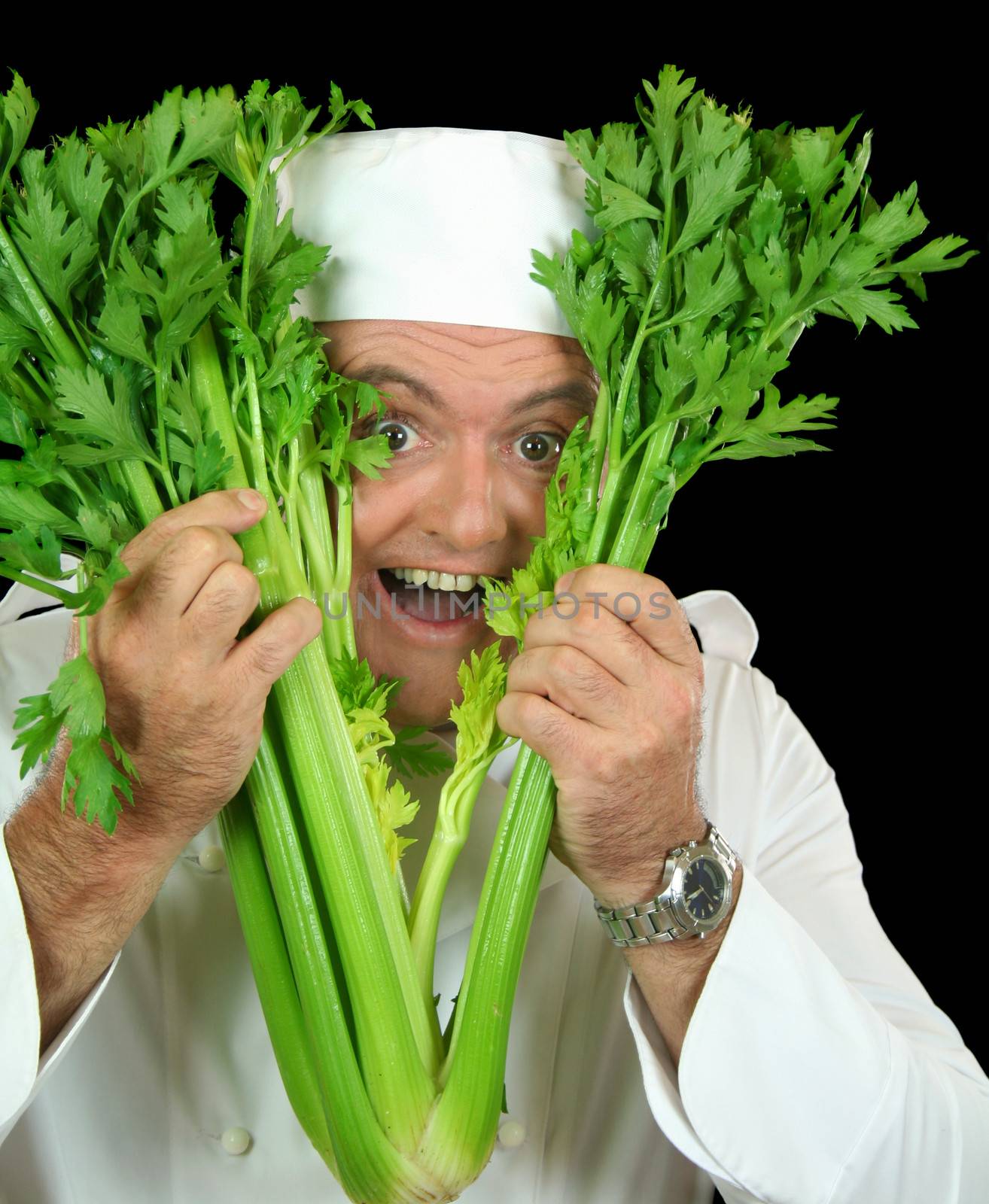 Peekaboo chef pops his head through a bunch of fresh celery.
