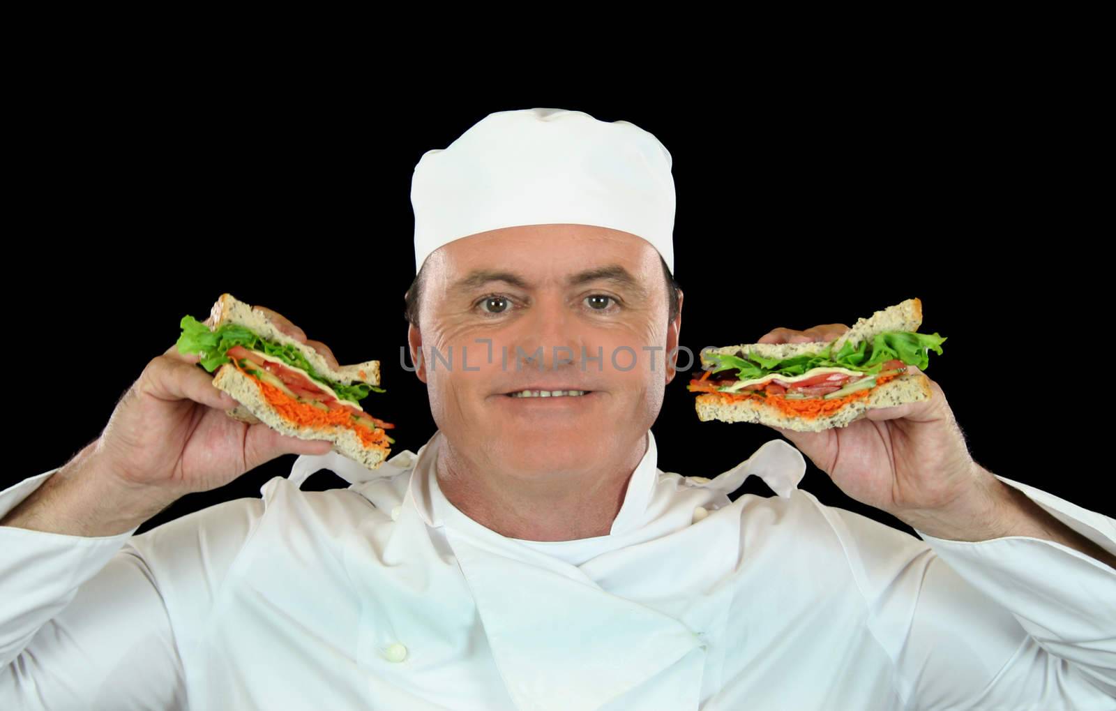 Smiling chef holds up healthy salad sandwich.